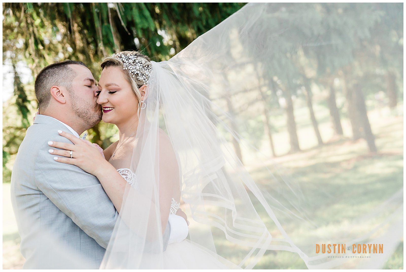 spring wedding posing ideas with bride holding her groom as her veil flows in the wind