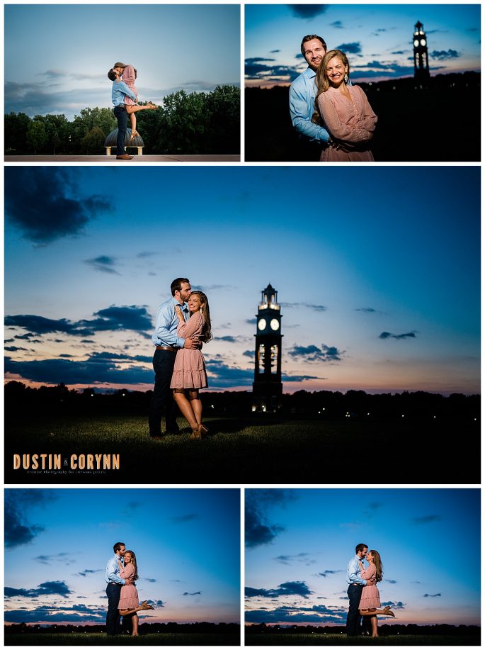 sunset engagement photos with a clock tower lit up in the back ground with man holding woman as they smile at the camera