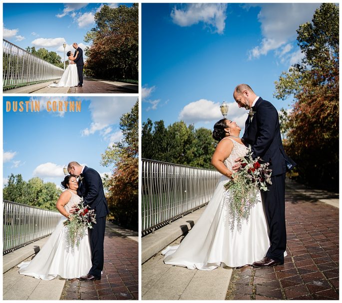 bride and groom standing on a bridge together as they laugh and embrace