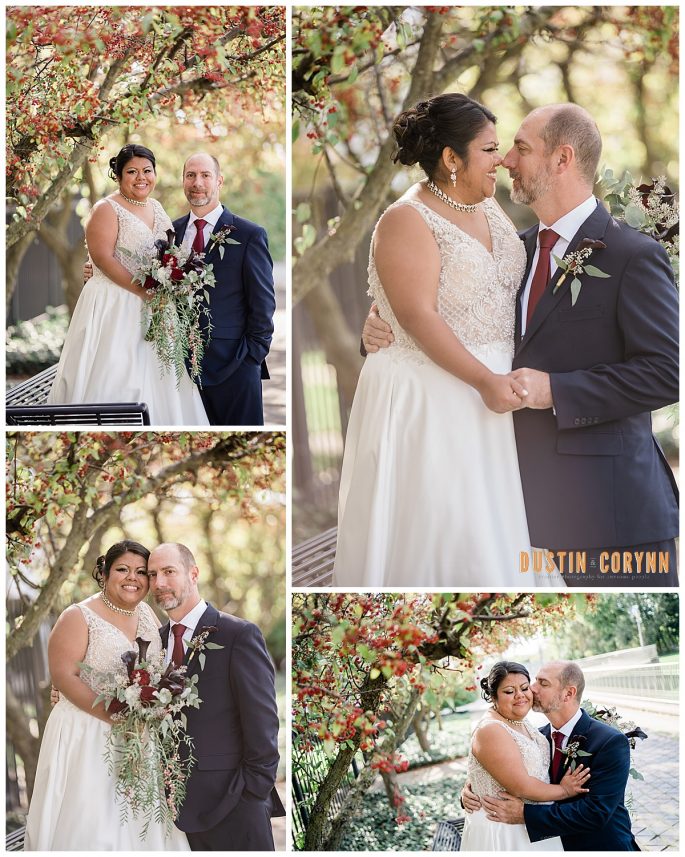 bride and groom embrace each other on a side walk under a red berry tree 