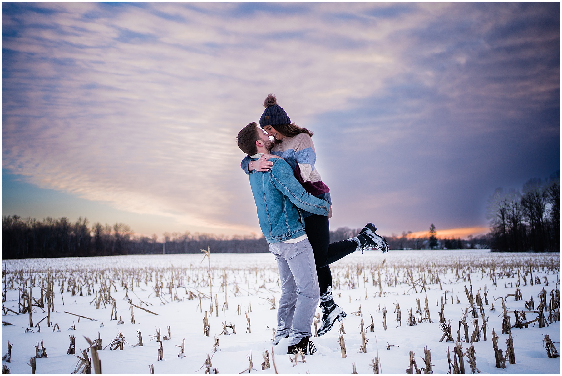man lifting woman and kissing during sunset at snowy winter fort wayne engagement