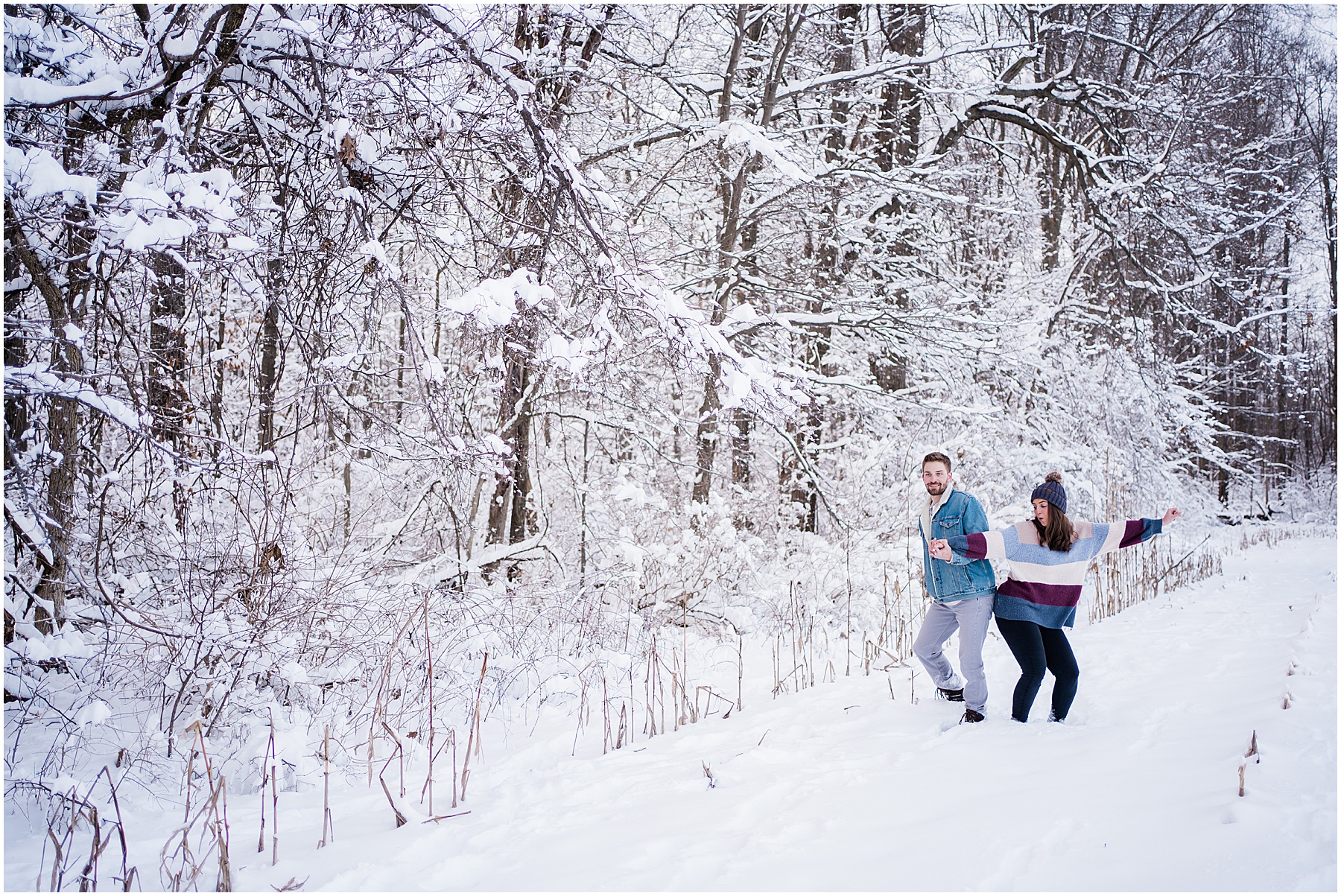 couple bumping hips and having fun during snowy winter fort wayne engagement