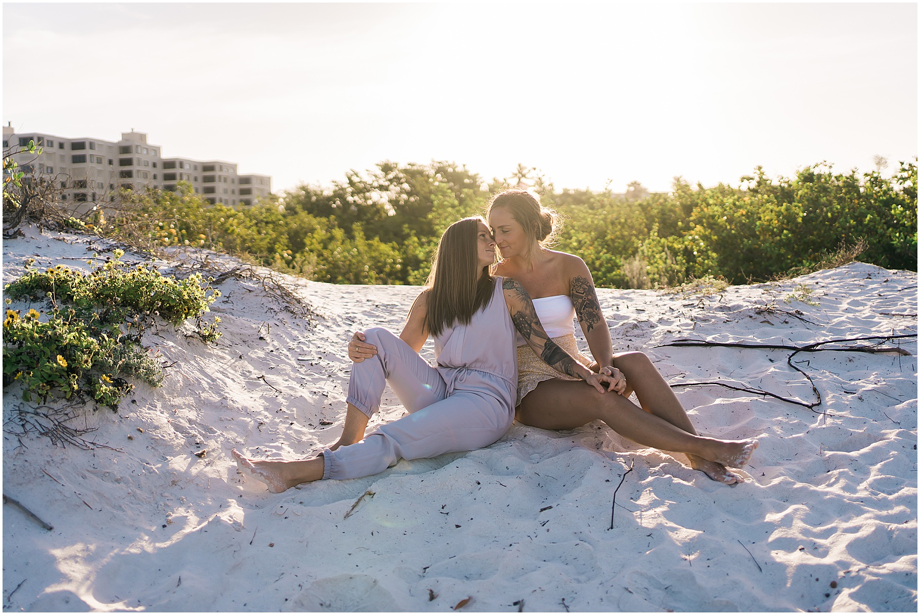 couple sitting on sandy beach engagement session