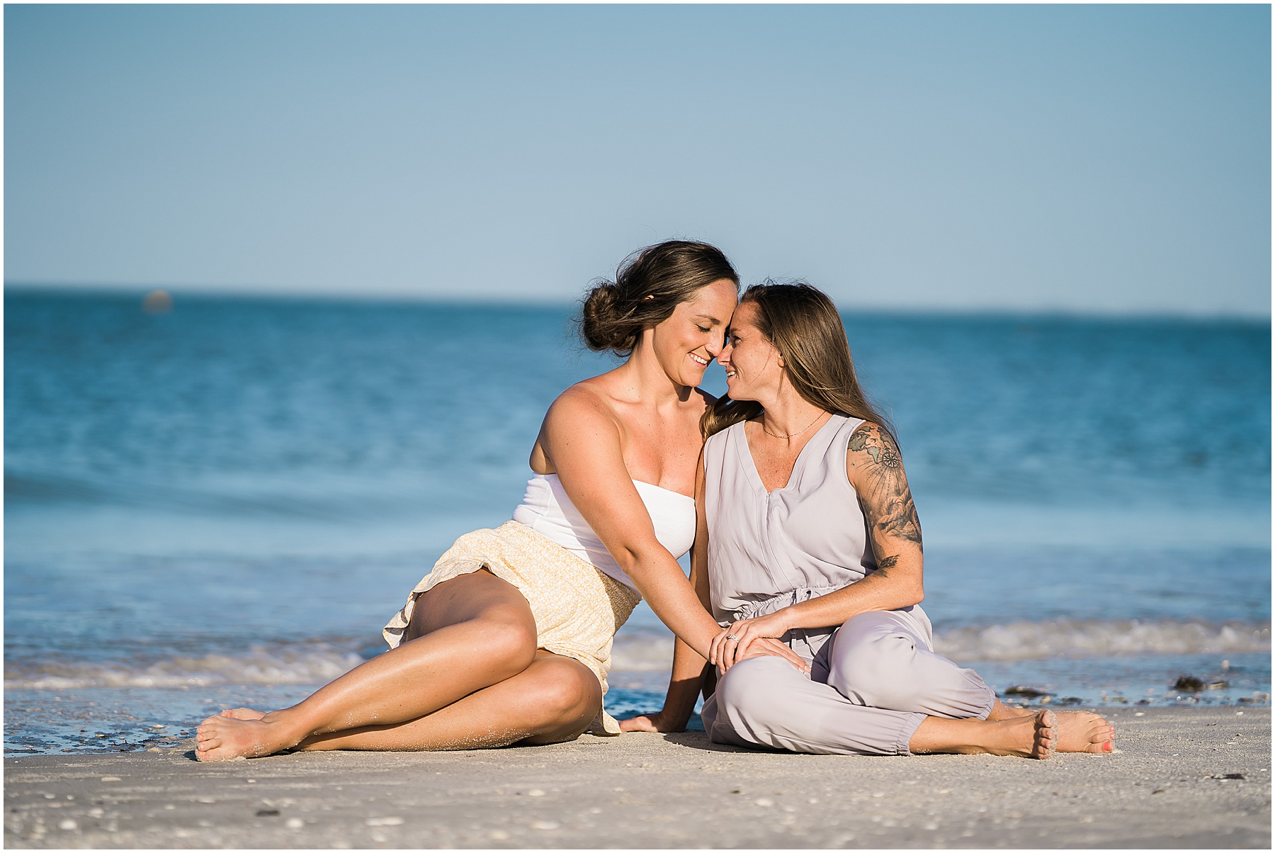 couple sitting on beach embracing during engagement session