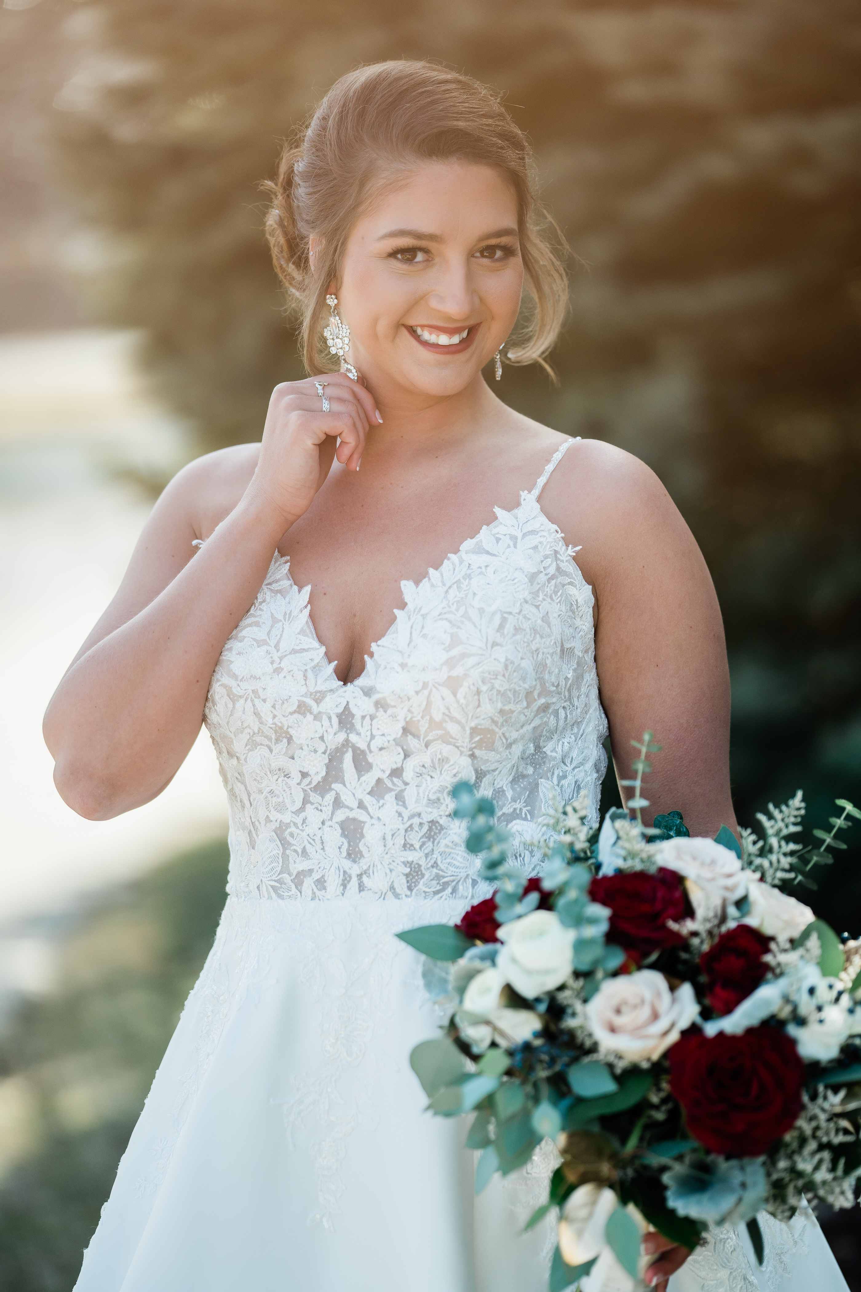 outdoor wedding photos of an Indianapolis bride in a lace wedding dress holding a burgundy rose wedding bouquet with the sun setting behind her