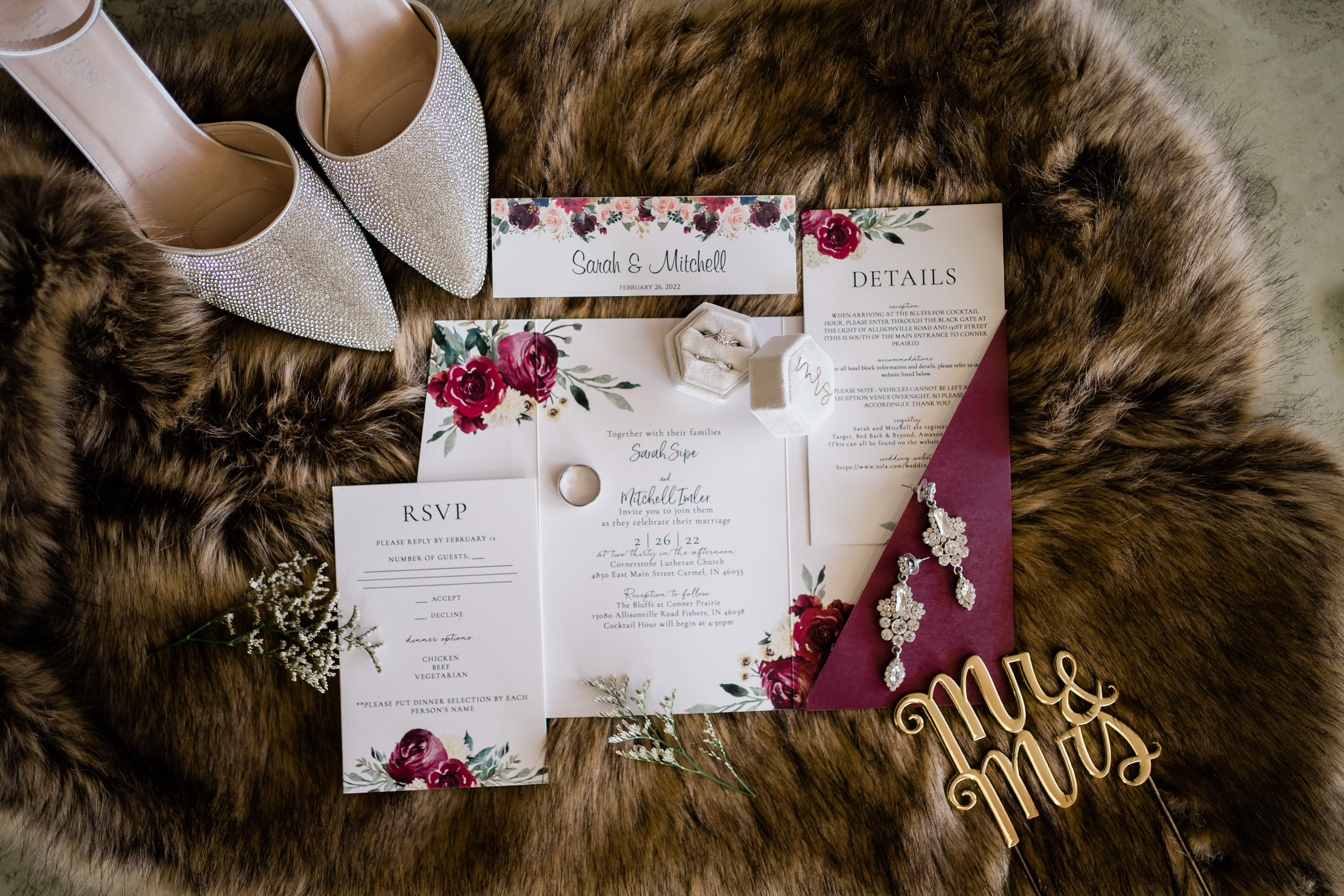 wedding details flatlay shot with wedding invitations in burgundy and brides shoes and earings