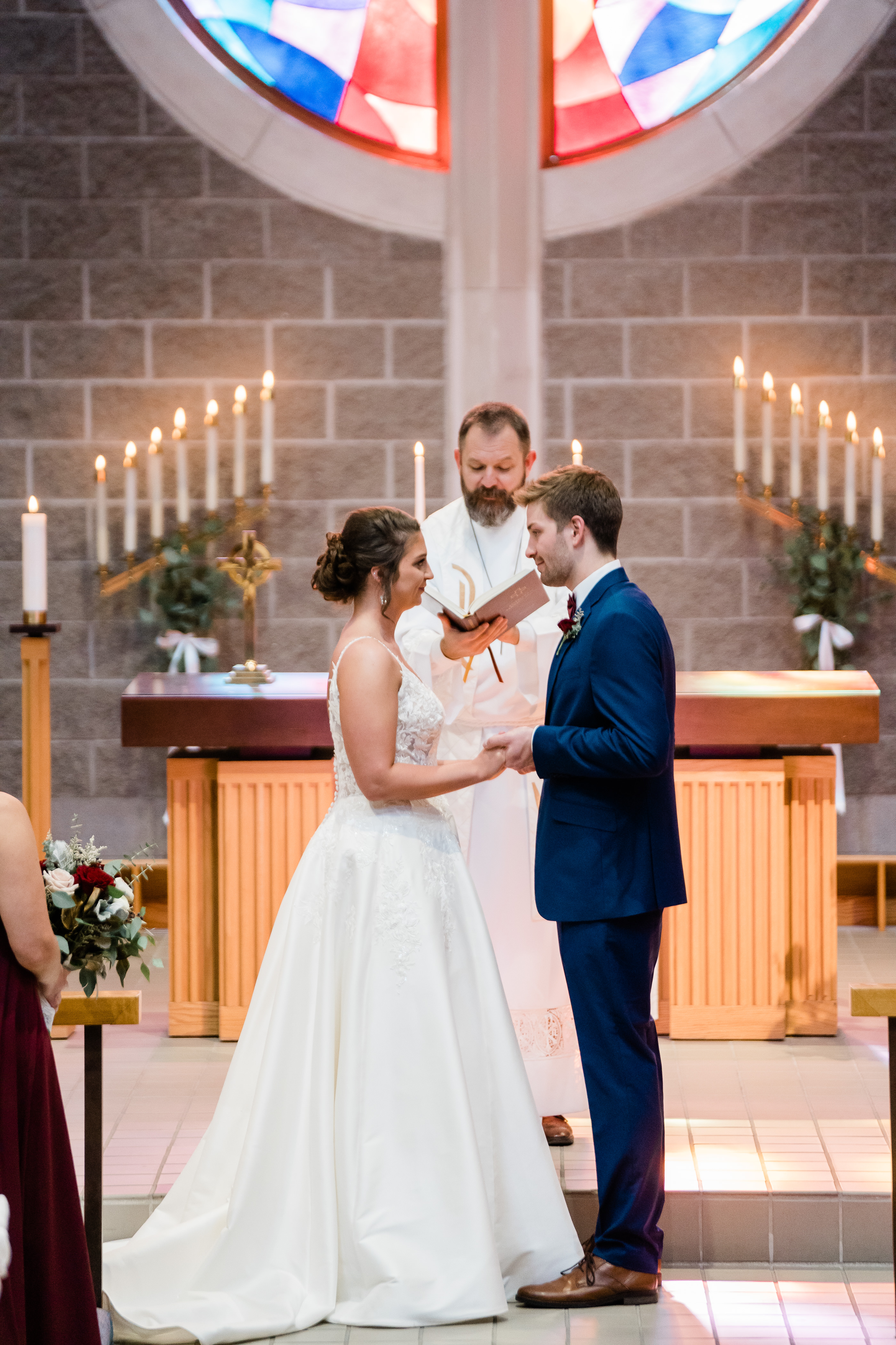 bride and groom at their church wedding ceremony holding hands and facing one another as their bishop marries them