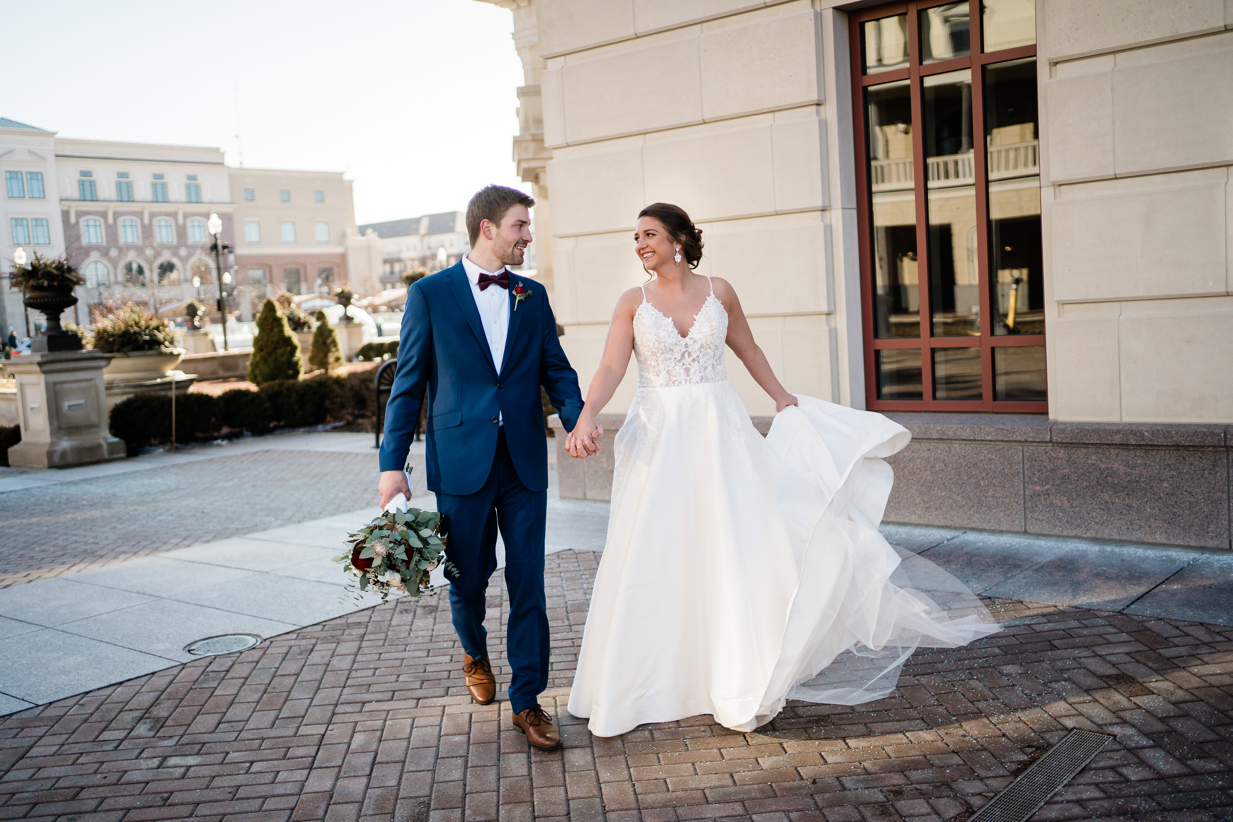bride and groom hold hands and walk through the courtyard of their Fort Wayne wedding venue 