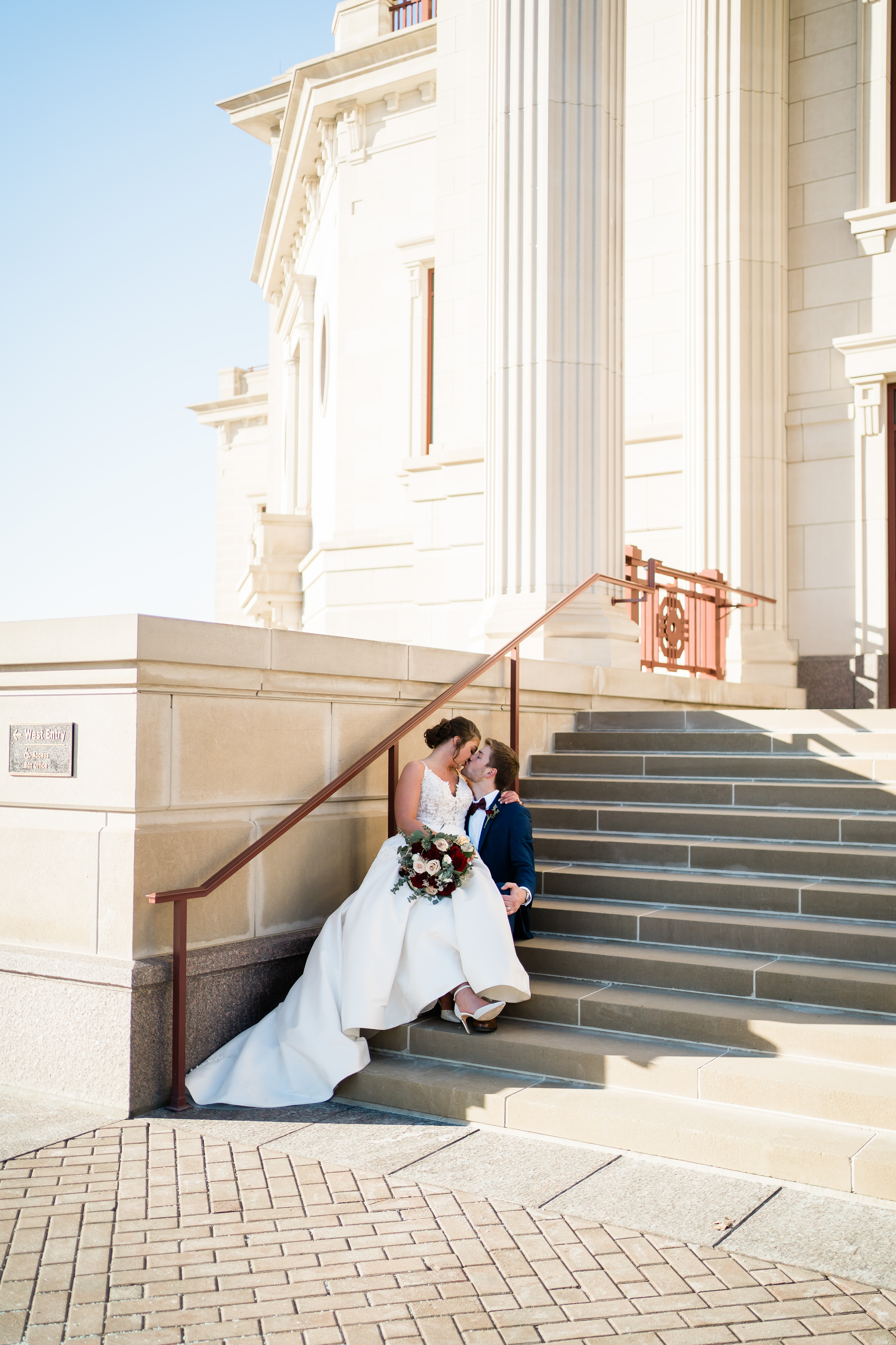 bride and groom sitting on outdoor stairs as they cuddle for their intimate wedding photos in Indianapolis