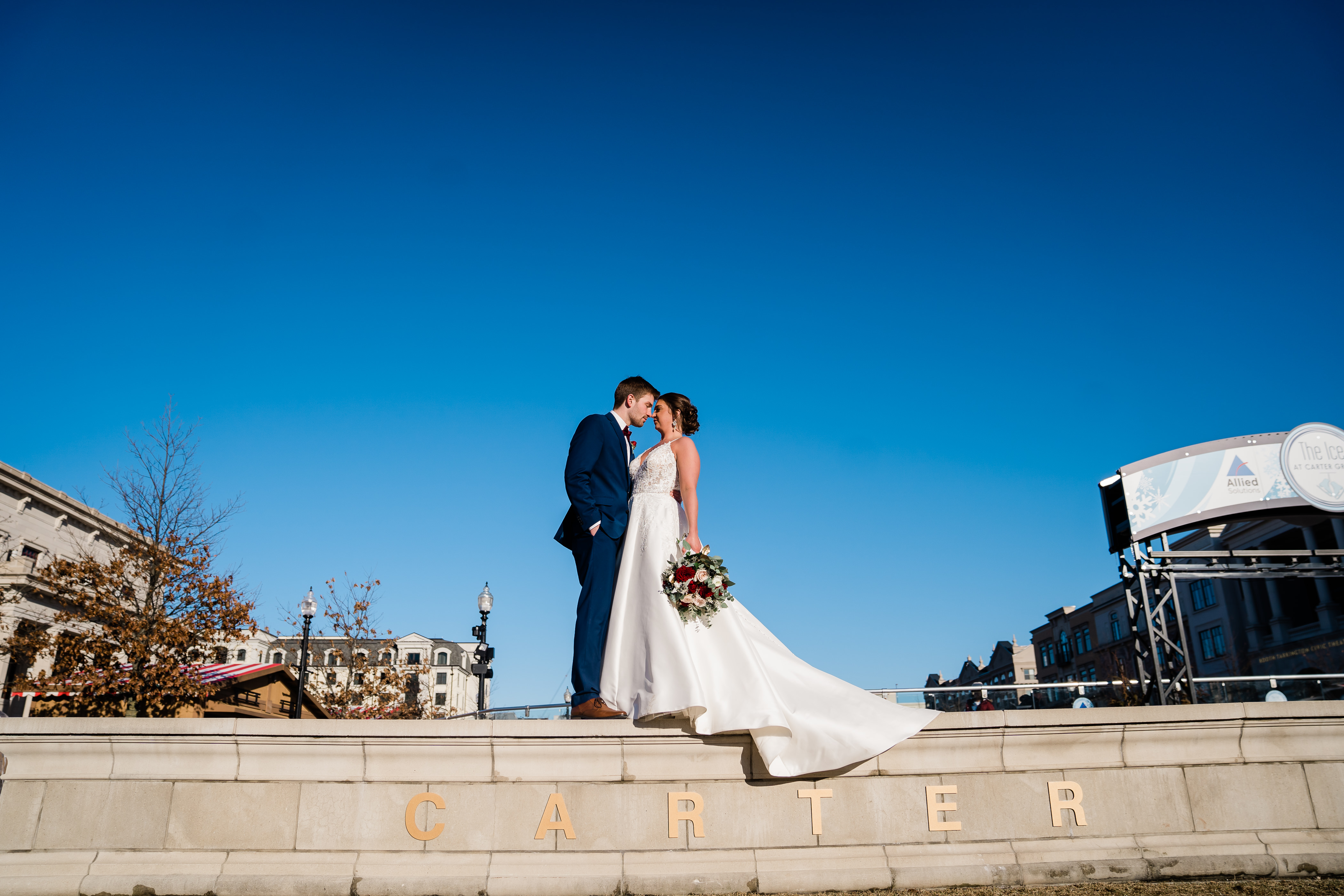 Fort Wayne outdoor bridals with bride and groom embracing on the top of stairs in a park with clear blue skies behind them
