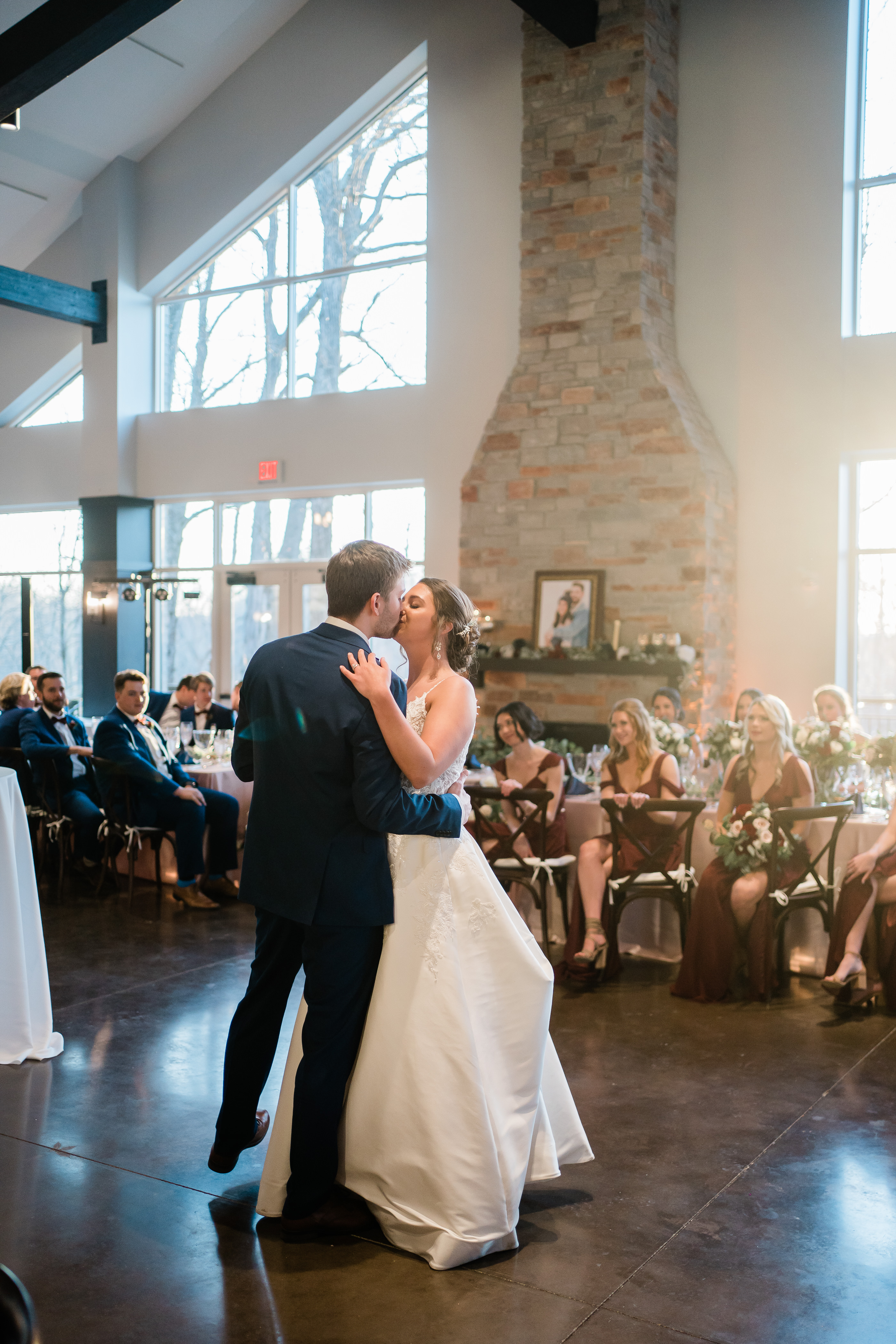 bride and groom have their first dance as the sunsets through the window of their wedding reception venue in Fort Wayne