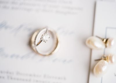 detail shot of wedding ring and engagement ring with brides earrings