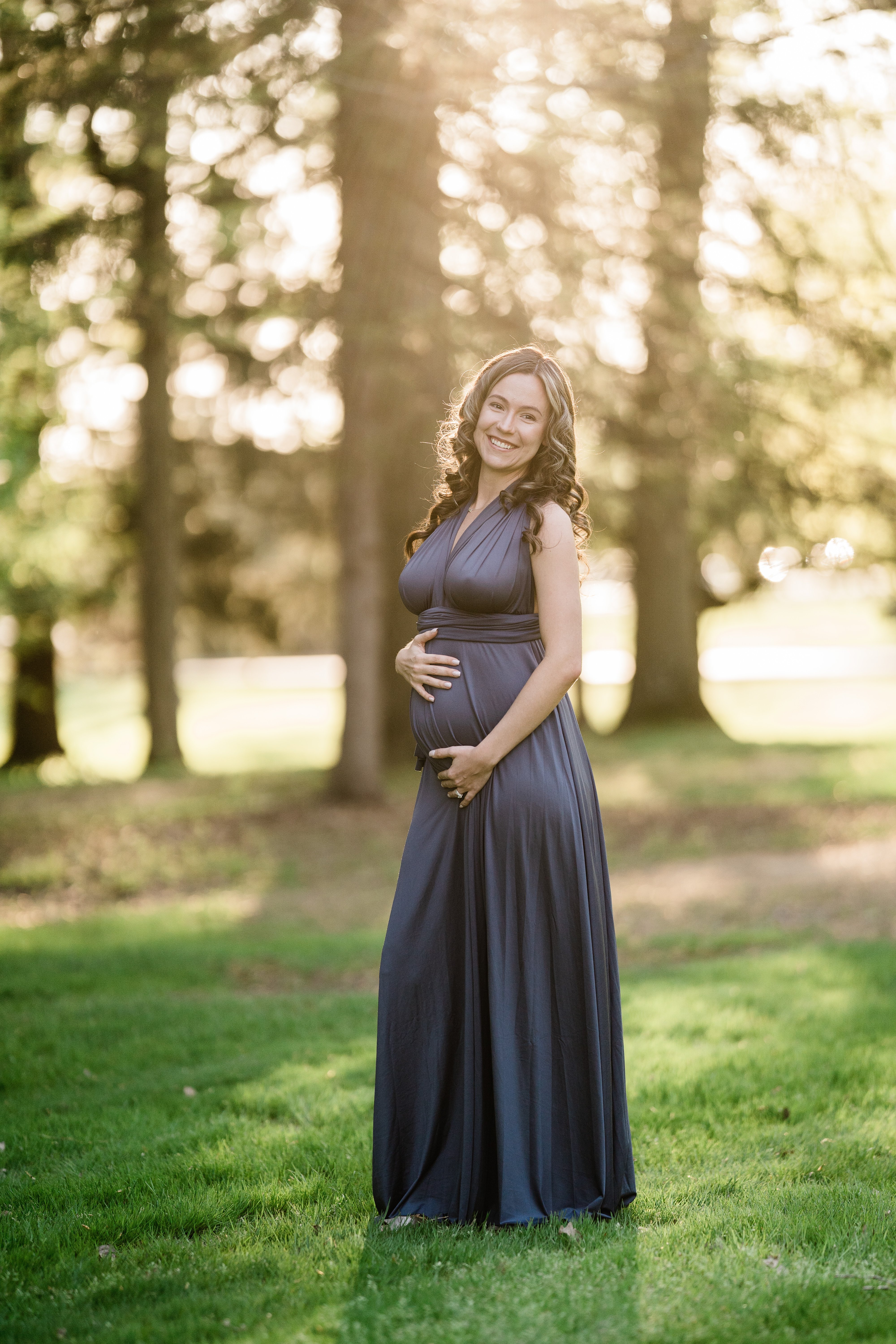 sunset maternity session in Fort Wayne with expecting mother in a deep blue gown holds her bump