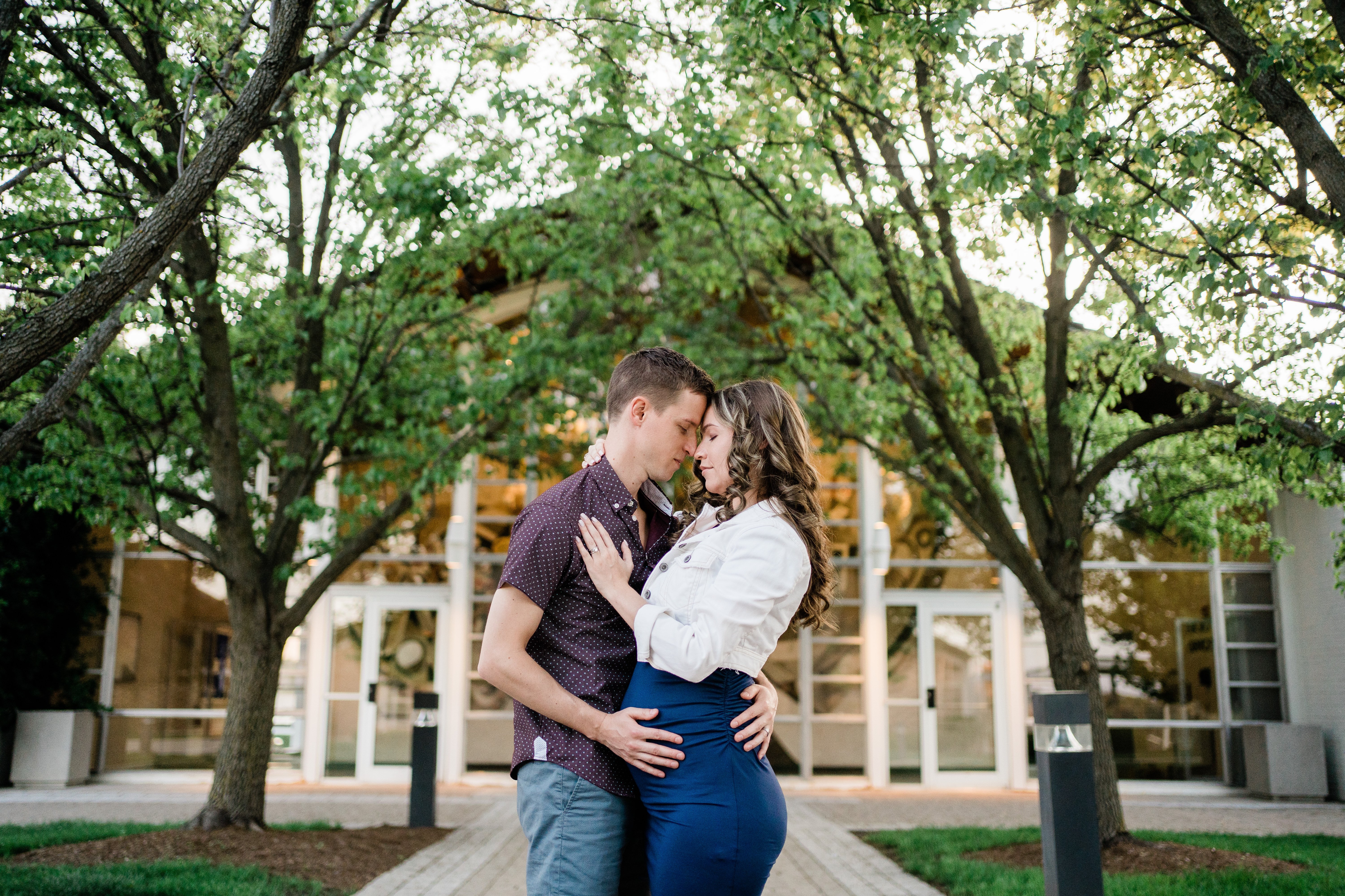 husband and wife embracing on campus in Fort Wayne for their maternity photos