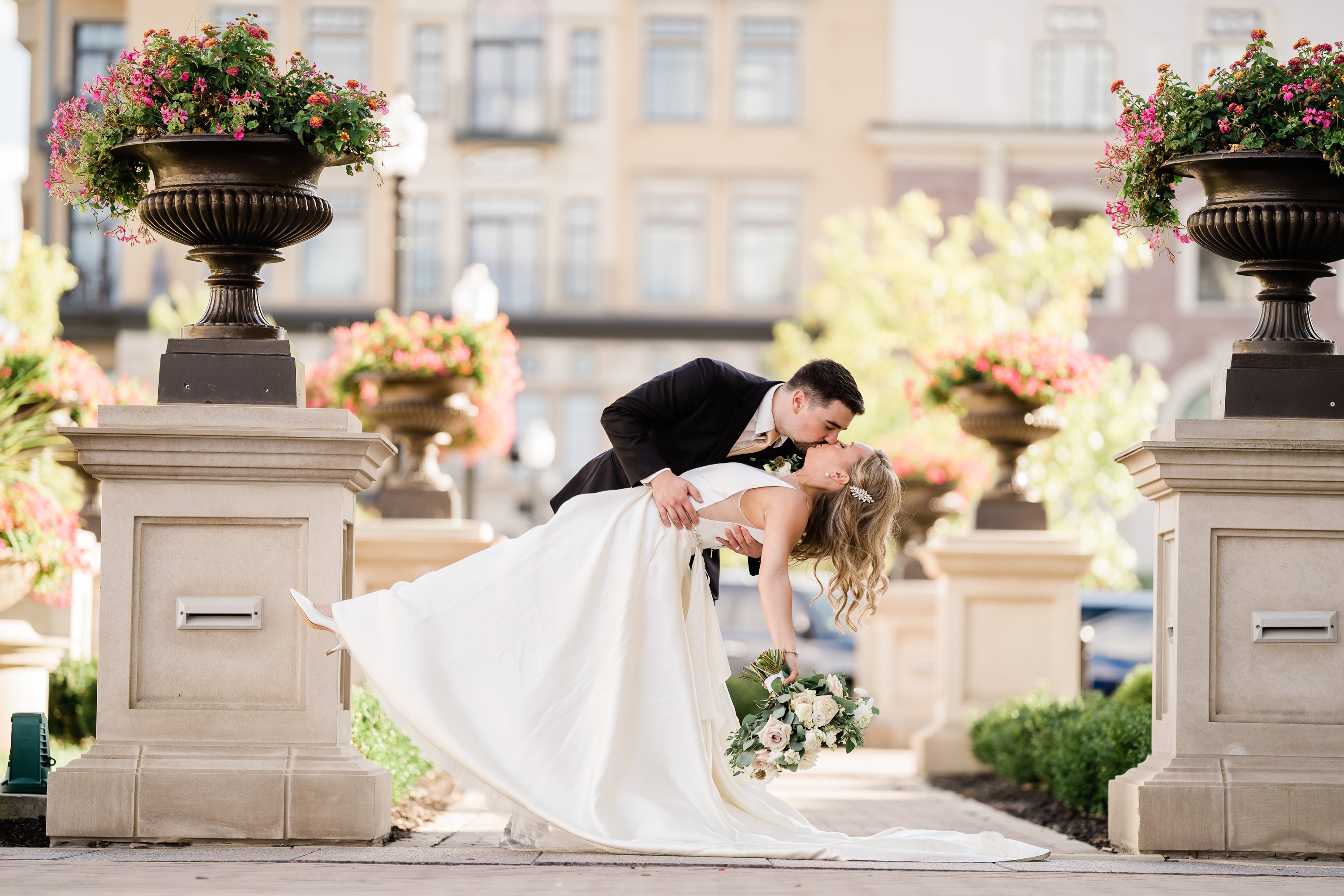 groom dipping his bride backwards and kissing her as they dance in a courtyard