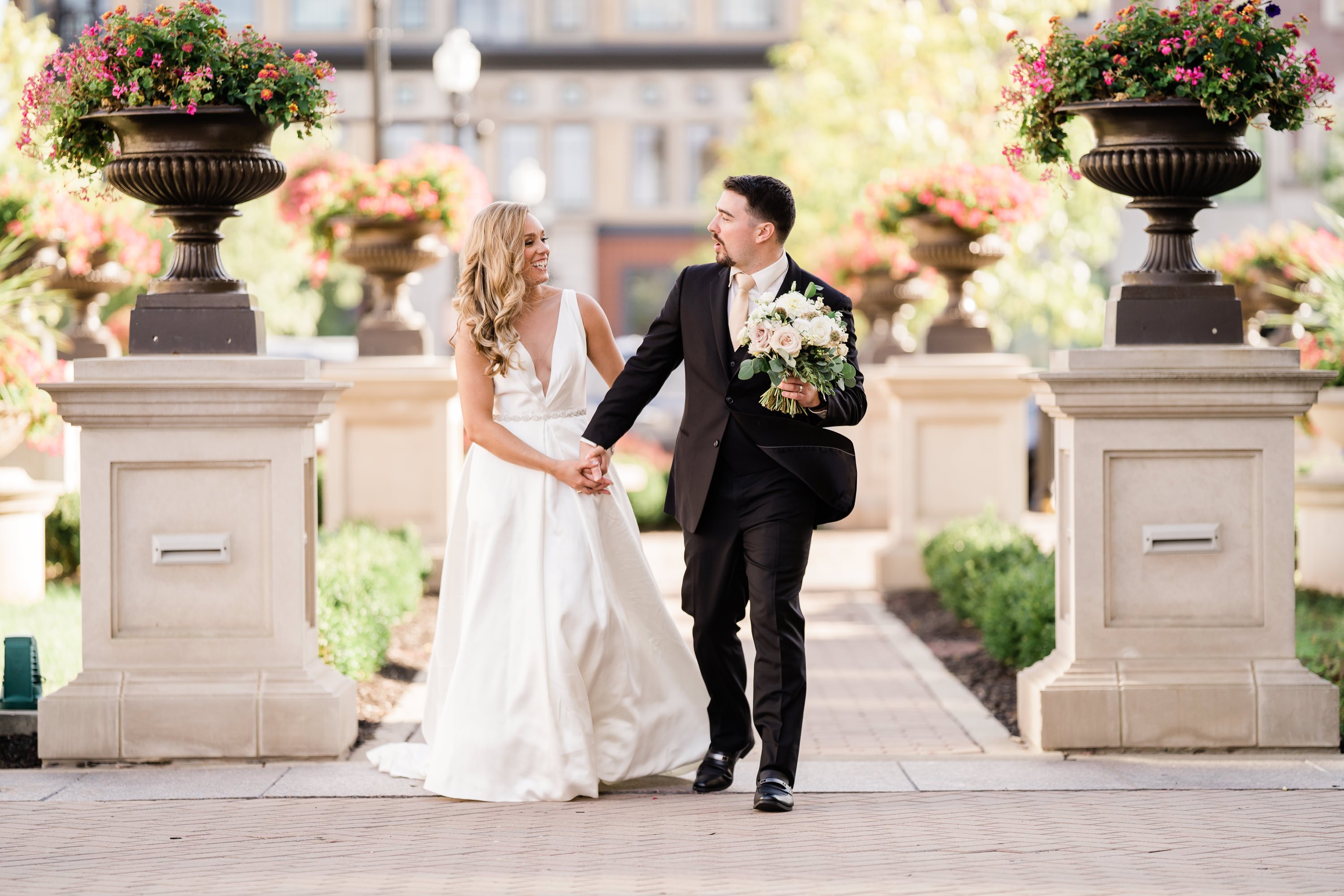 bride and groom holding hands and walking through a courtyard captured by Fort Wayne wedding photographers 
