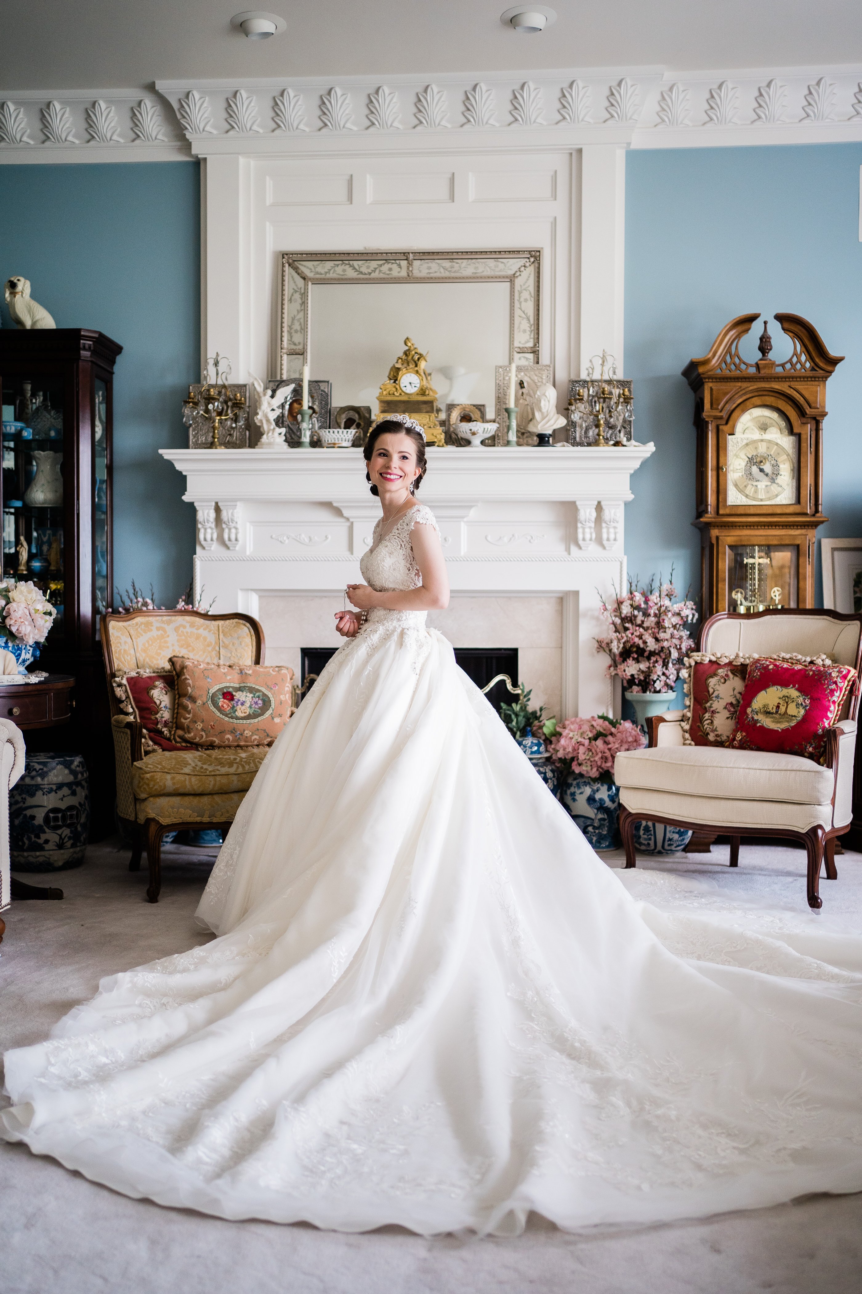 bride standing in her bridal suite with her wedding dress spread out of the floor as she smiles over her shoulder 