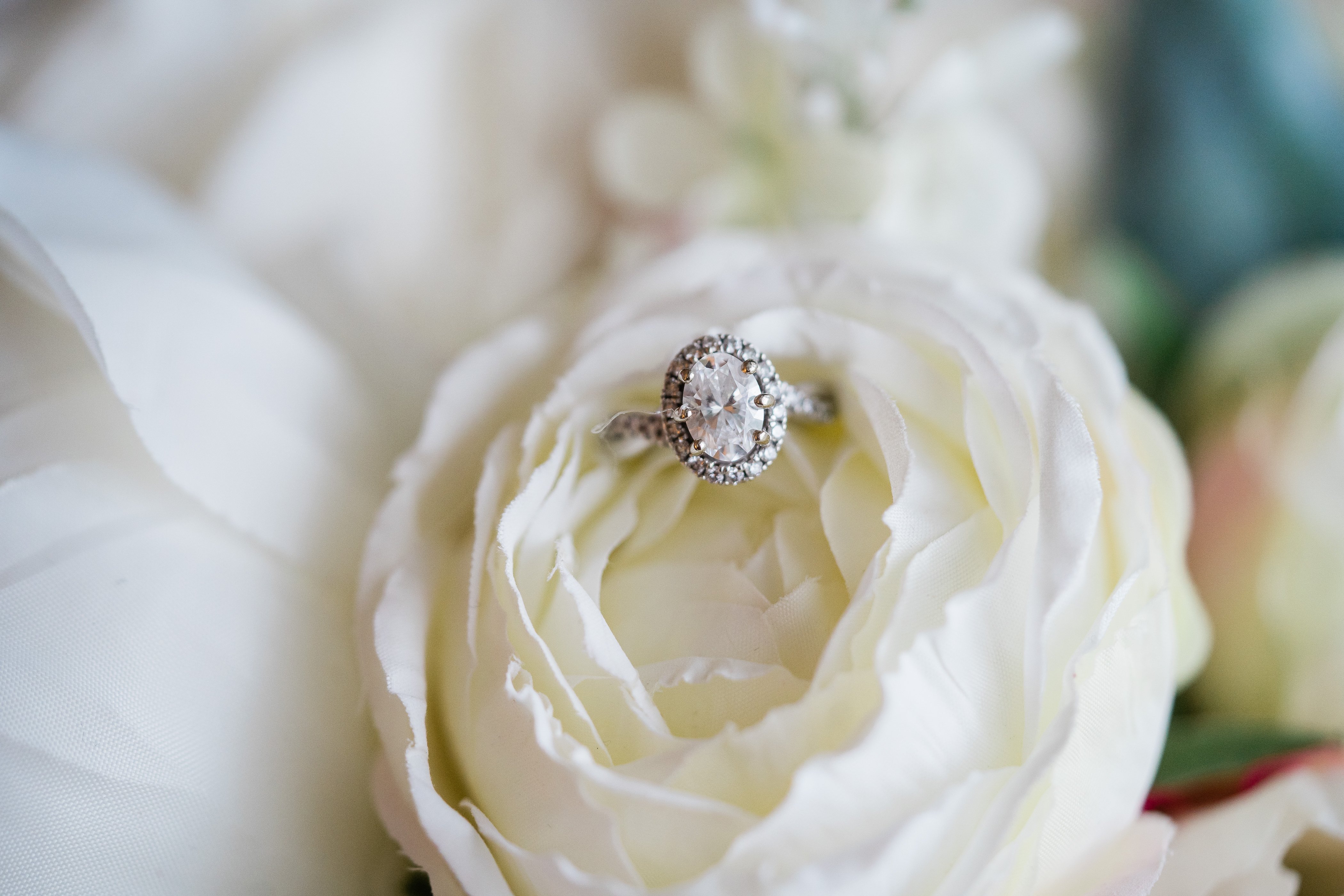 oval diamond wedding ring sitting on top of a white flower captured by Fort Wayne wedding photographers