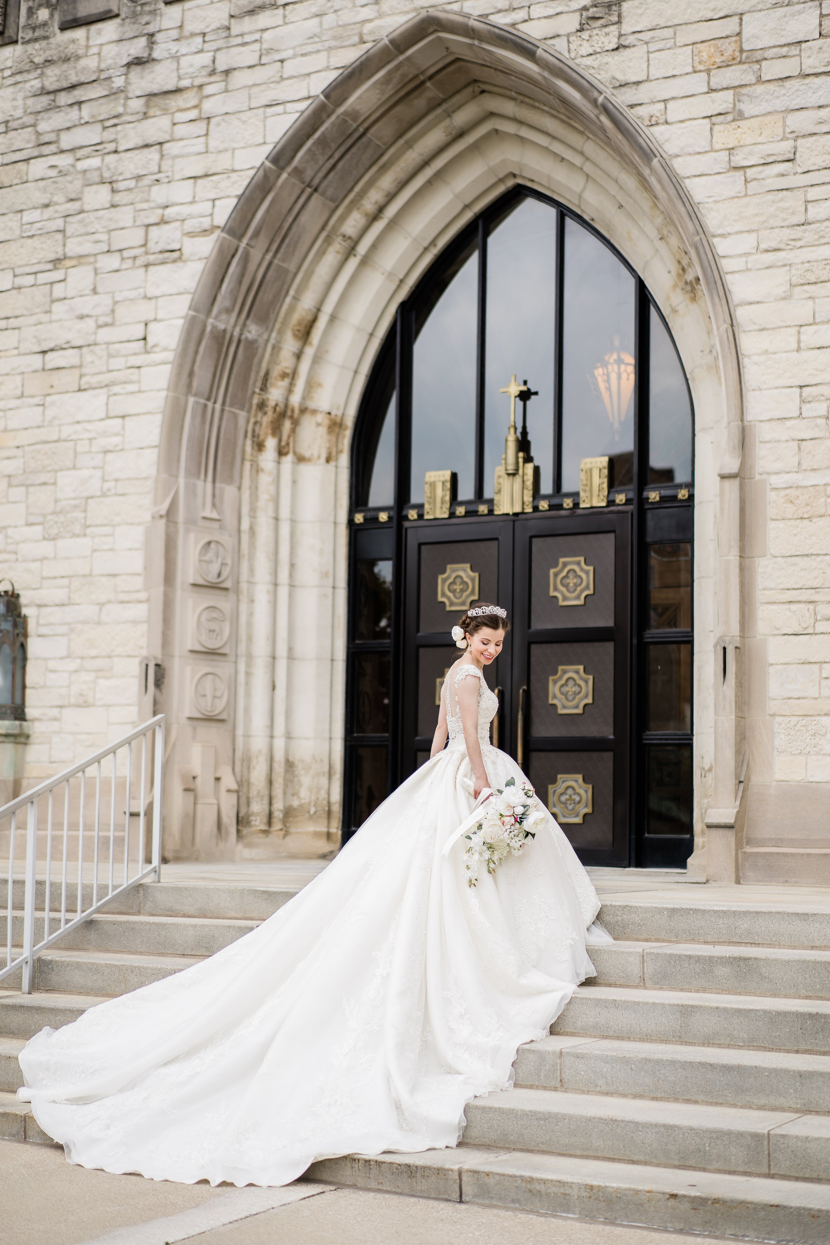 bride in a ballgown wedding dress in a 10 foot train walks up the stairs of a castle wedding venue
