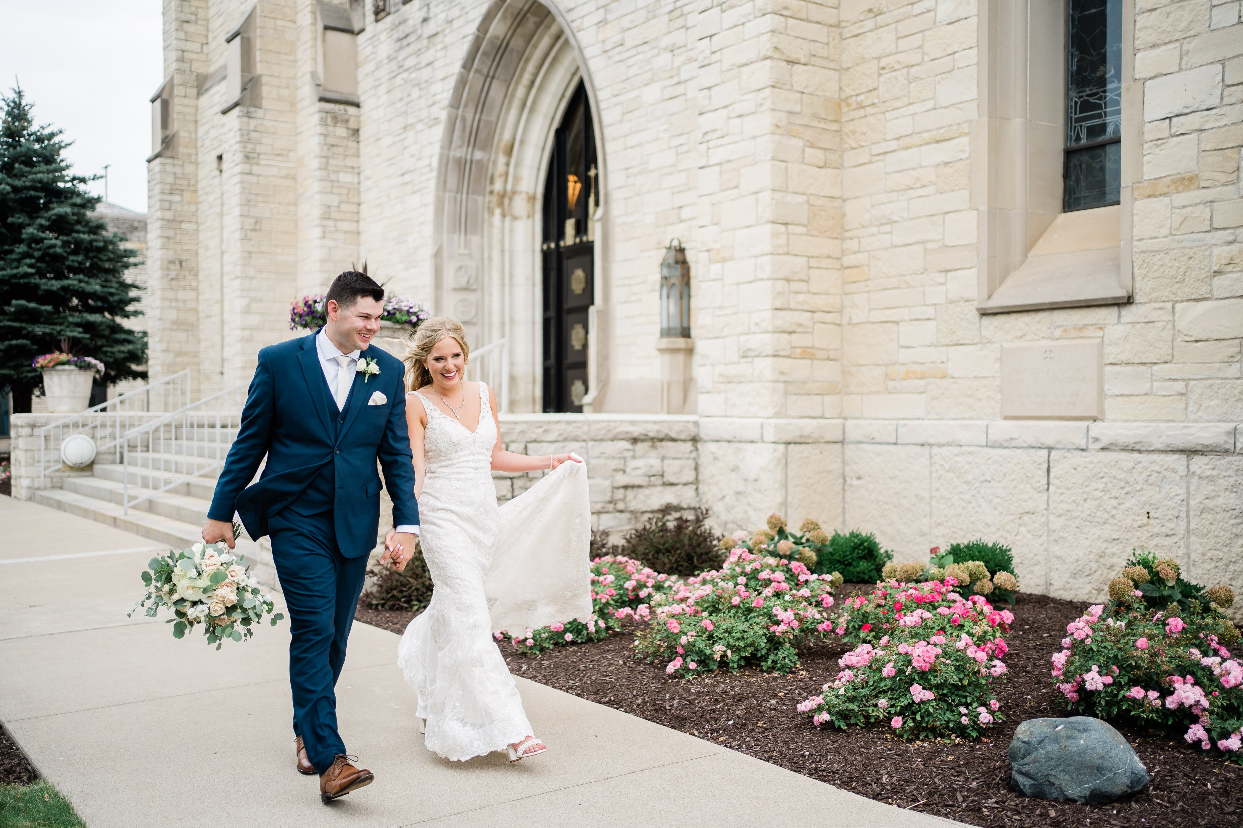 bride and groom holding hands and walking around their outdoor wedding venue in Fort Wayne 