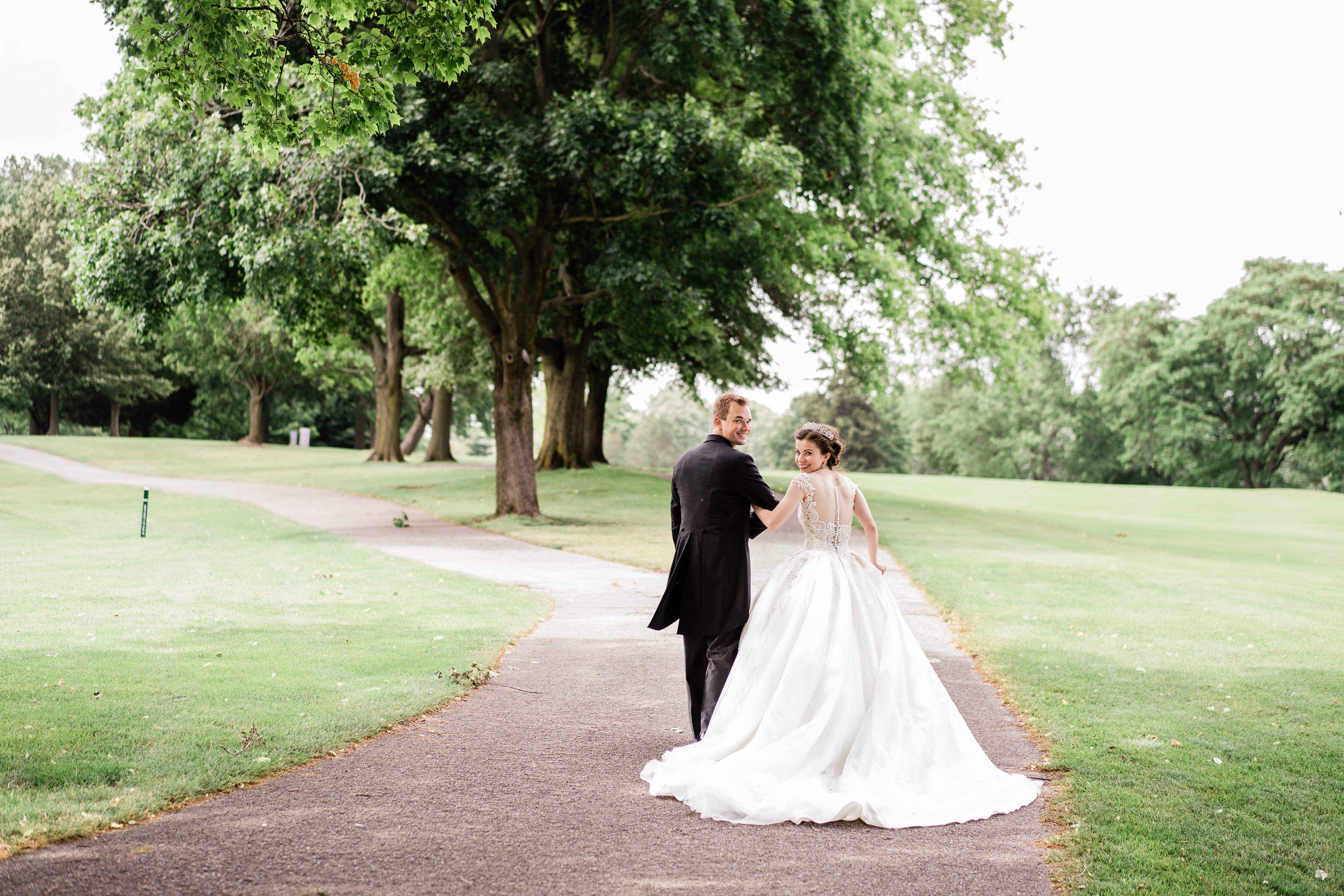 outdoor wedding photos in Fort Wayne with bride and groom walking down a path together 