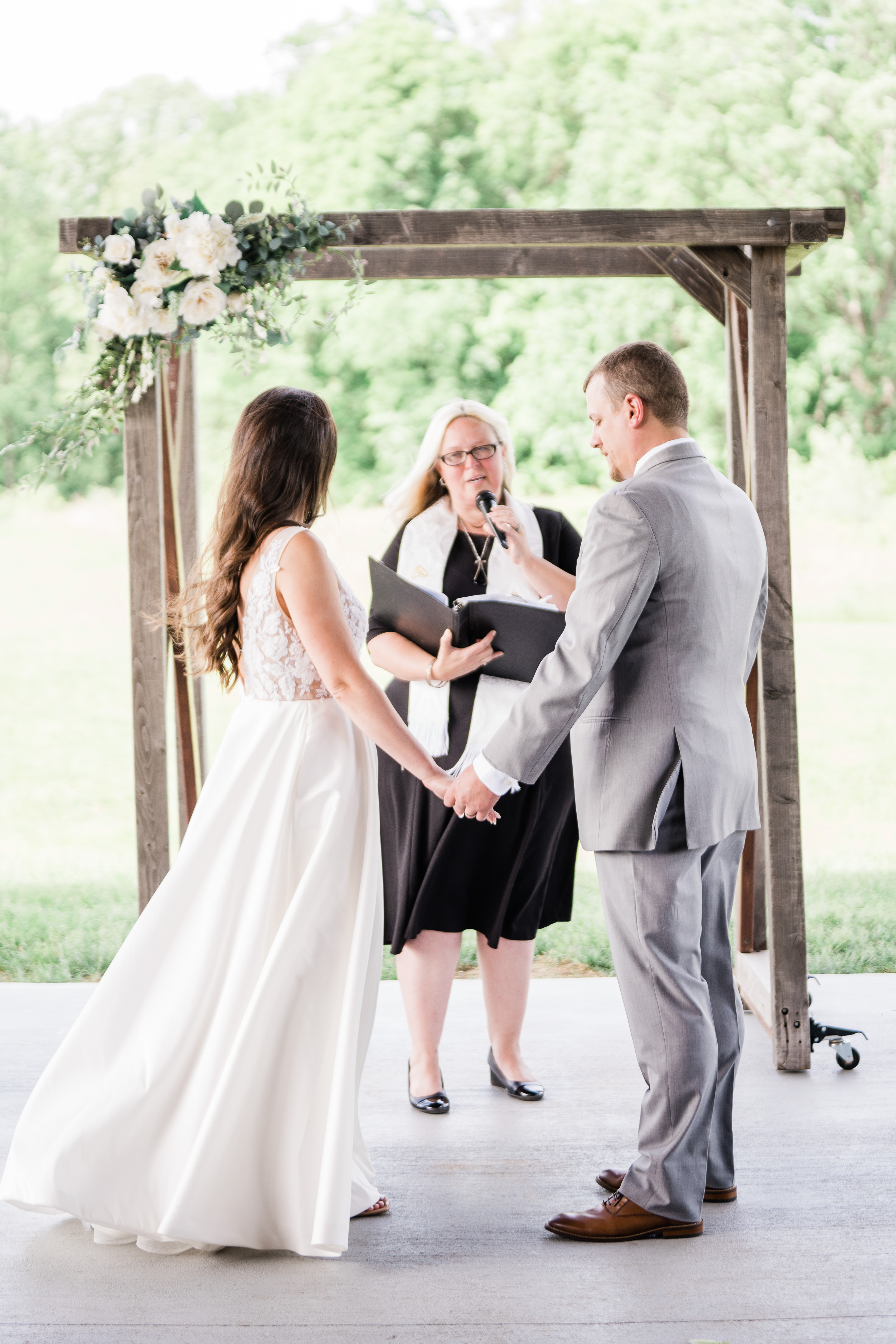 wedding ceremony outdoors with bride and groom holding hands while their officiant shares a few words
