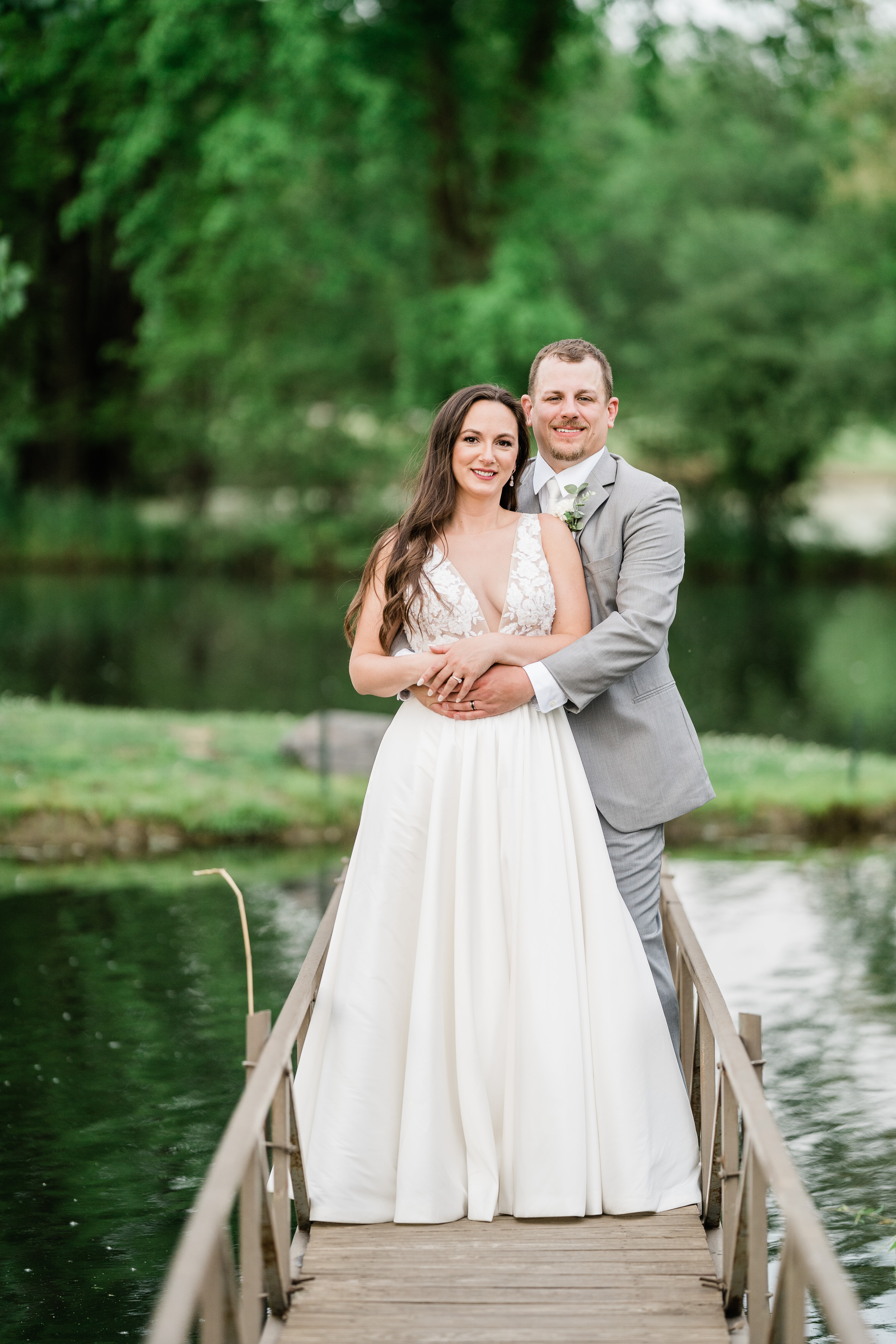bride and groom standing on a bridge while posing for their Fort Wayne wedding photos