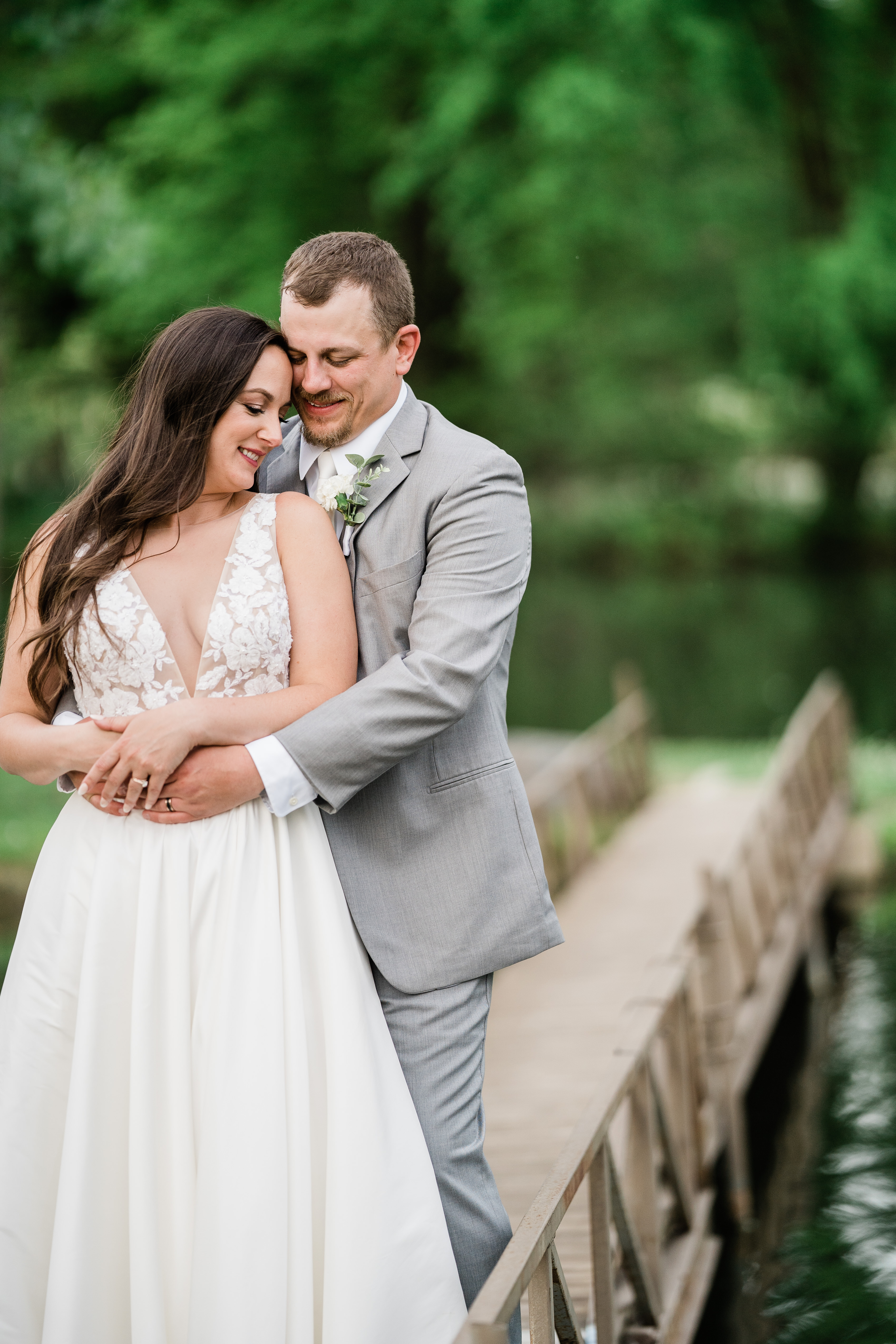 wedding portraits with bride on a bridge being cuddled by her groom taken by Fort Wayne wedding photographers