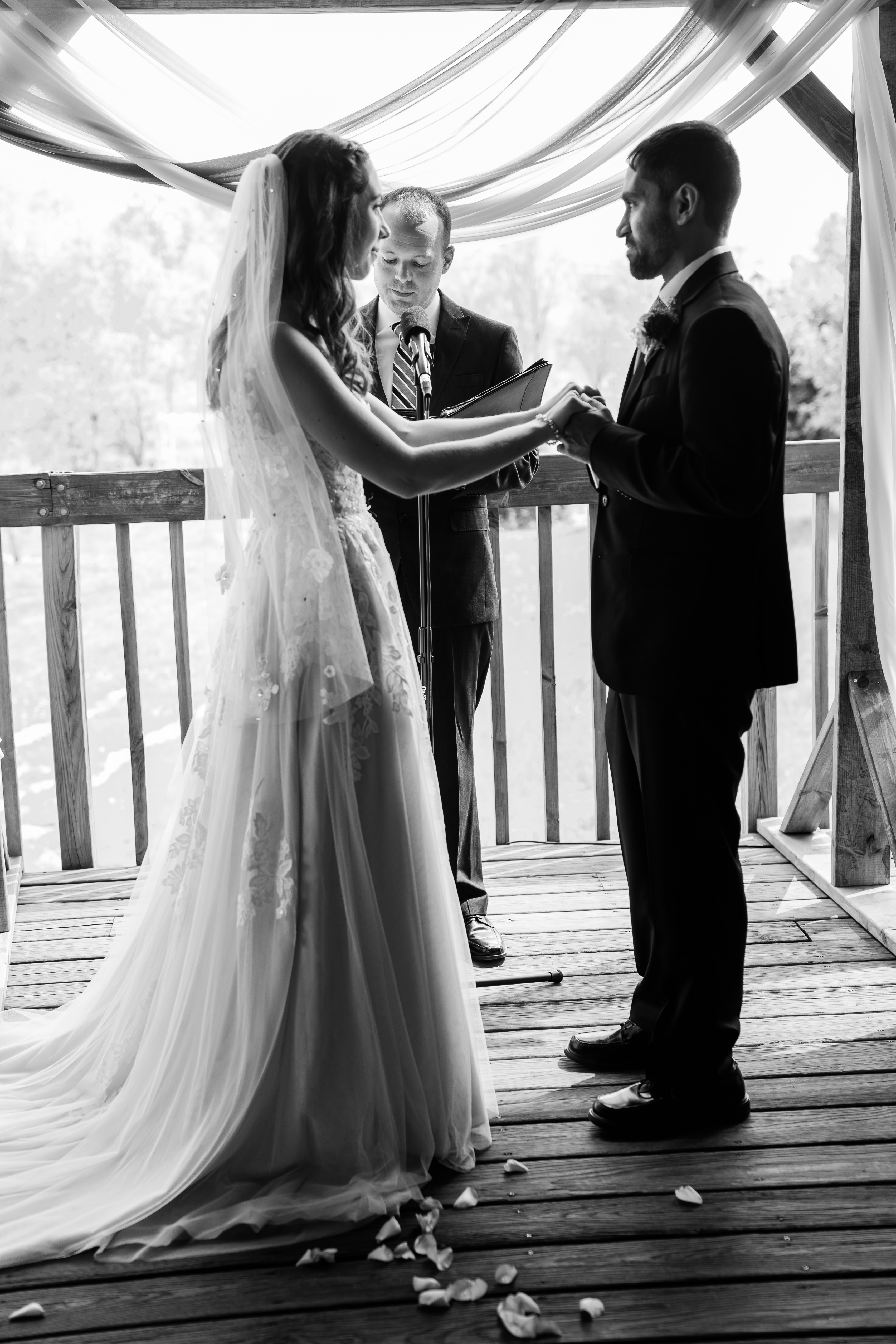 bride and groom holding hands during their ceremony on an outdoor pavilion photographed by Fort Wayne wedding photographer
