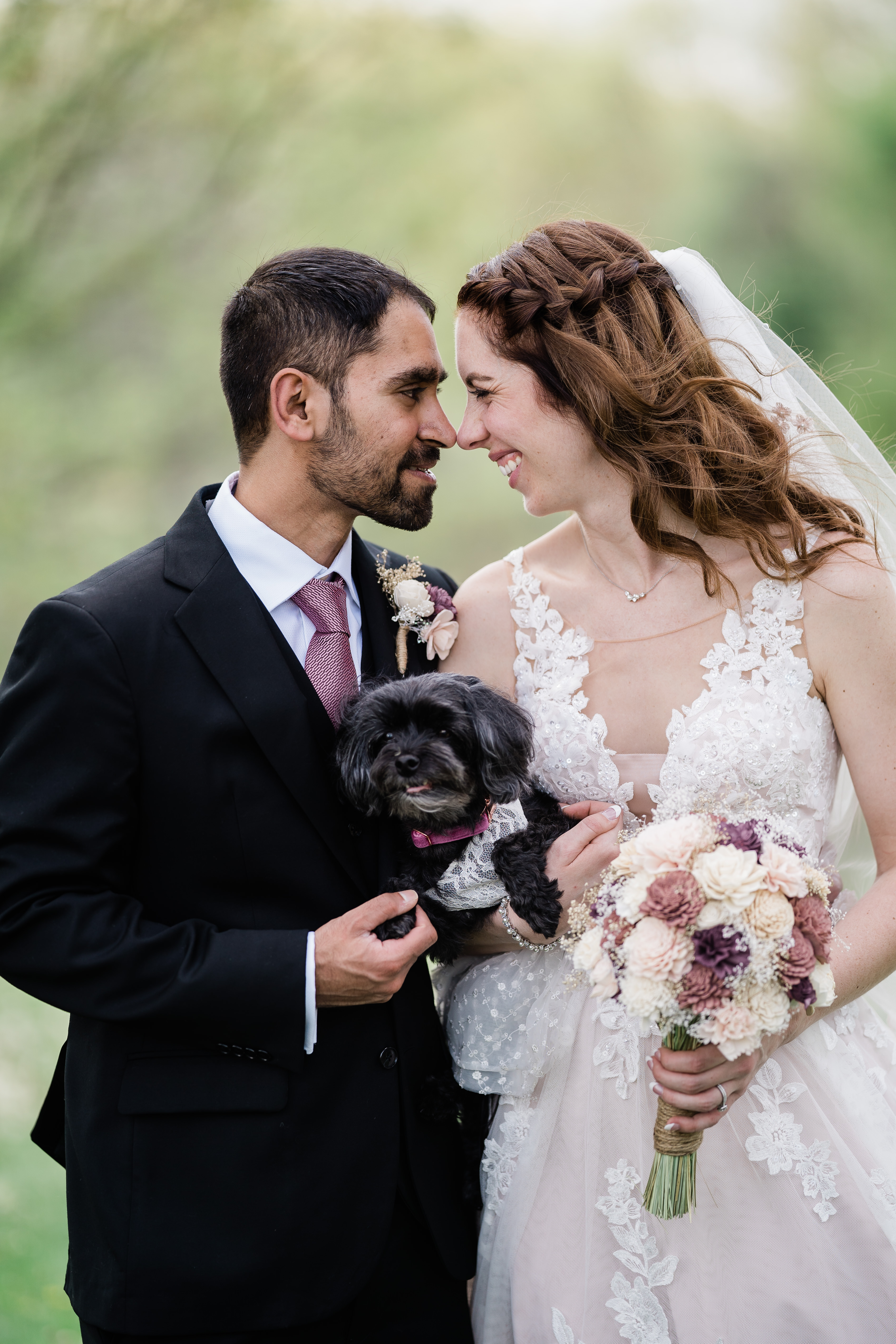 bride adn groom leaning their foreheads together until their noses touch as they hold their little black dog taken by Fort Wayne wedding photographers
