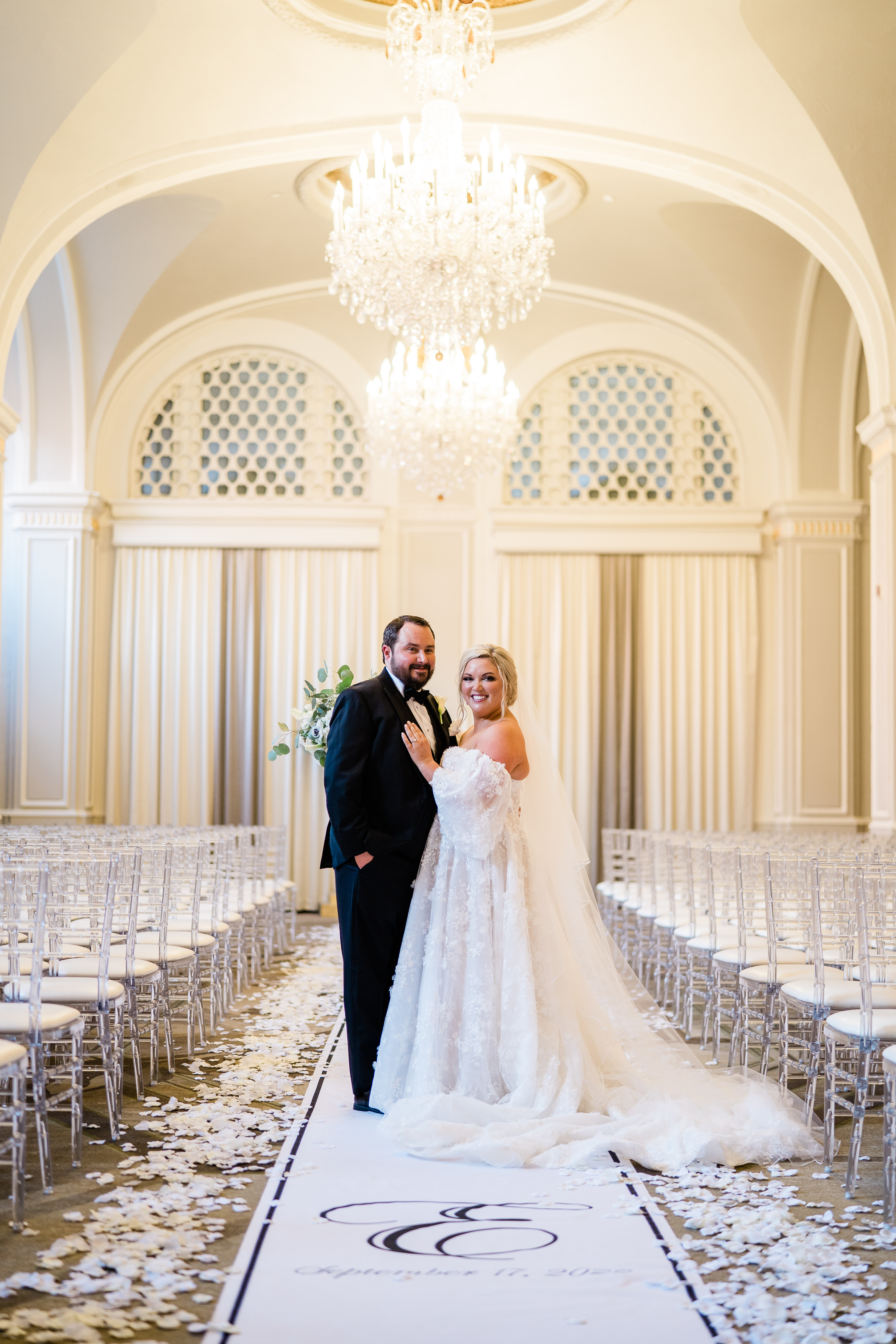 bride and groom standing in an elegant ceremony hall with chandeliers overhead