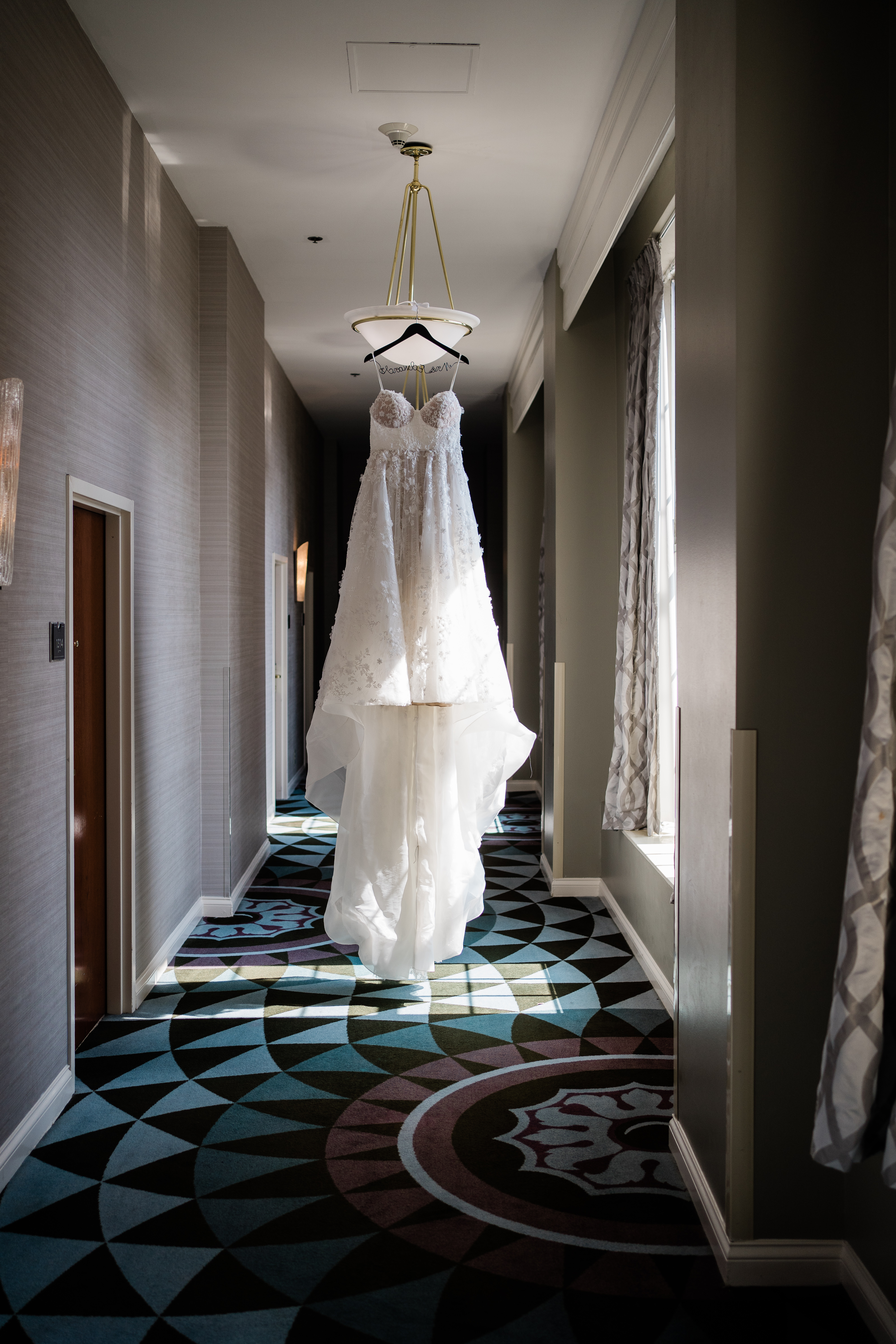 brides dress hanging in a hallway at the wedding venue for a downtown wedding taken by Fort Wayne wedding photographers