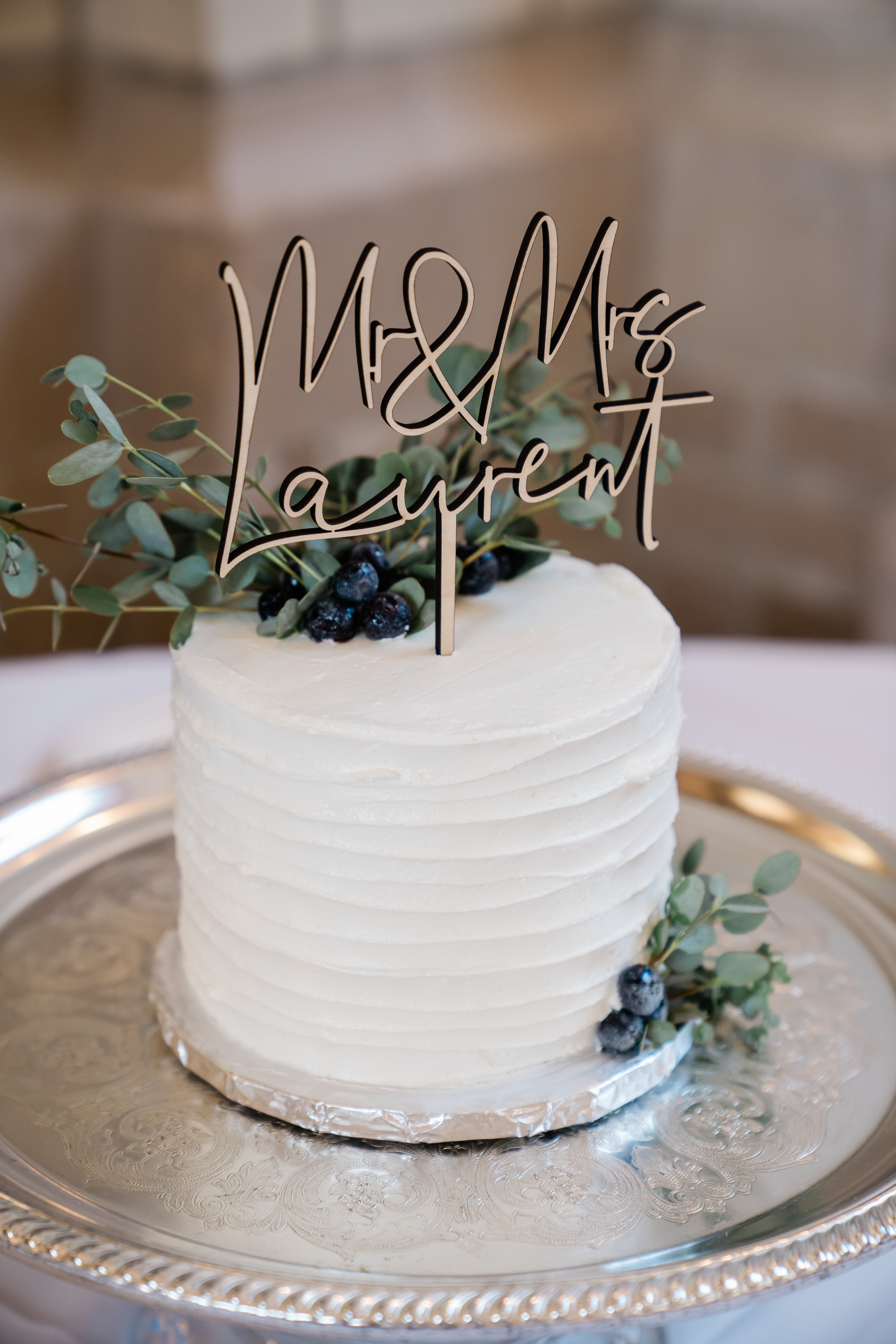 small wedding cake with greenery on top of the white buttercream
