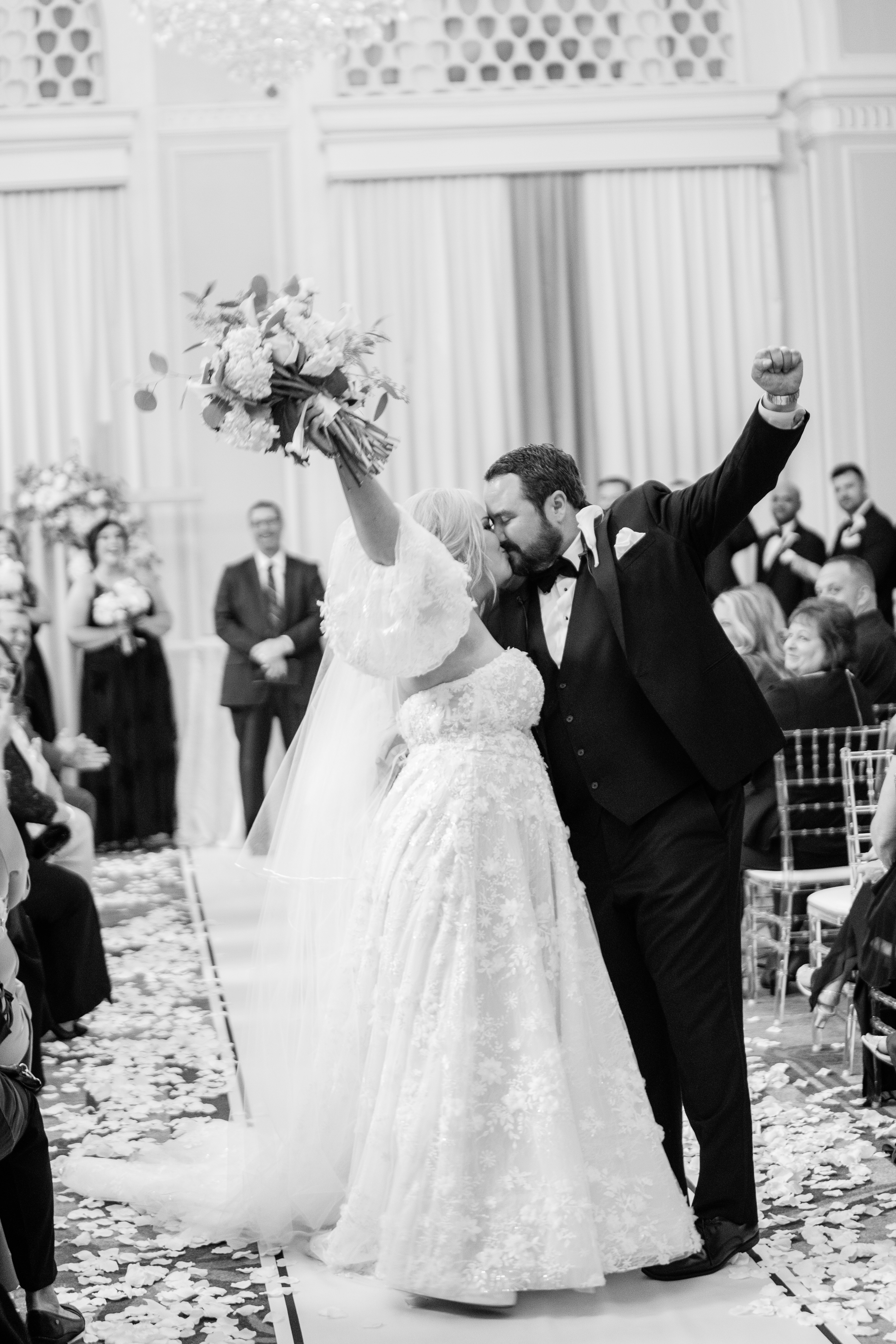 bride and groom leaving their wedding ceremony and kissing with their hands in the air in celebration captured by Fort Wayne wedding photographers