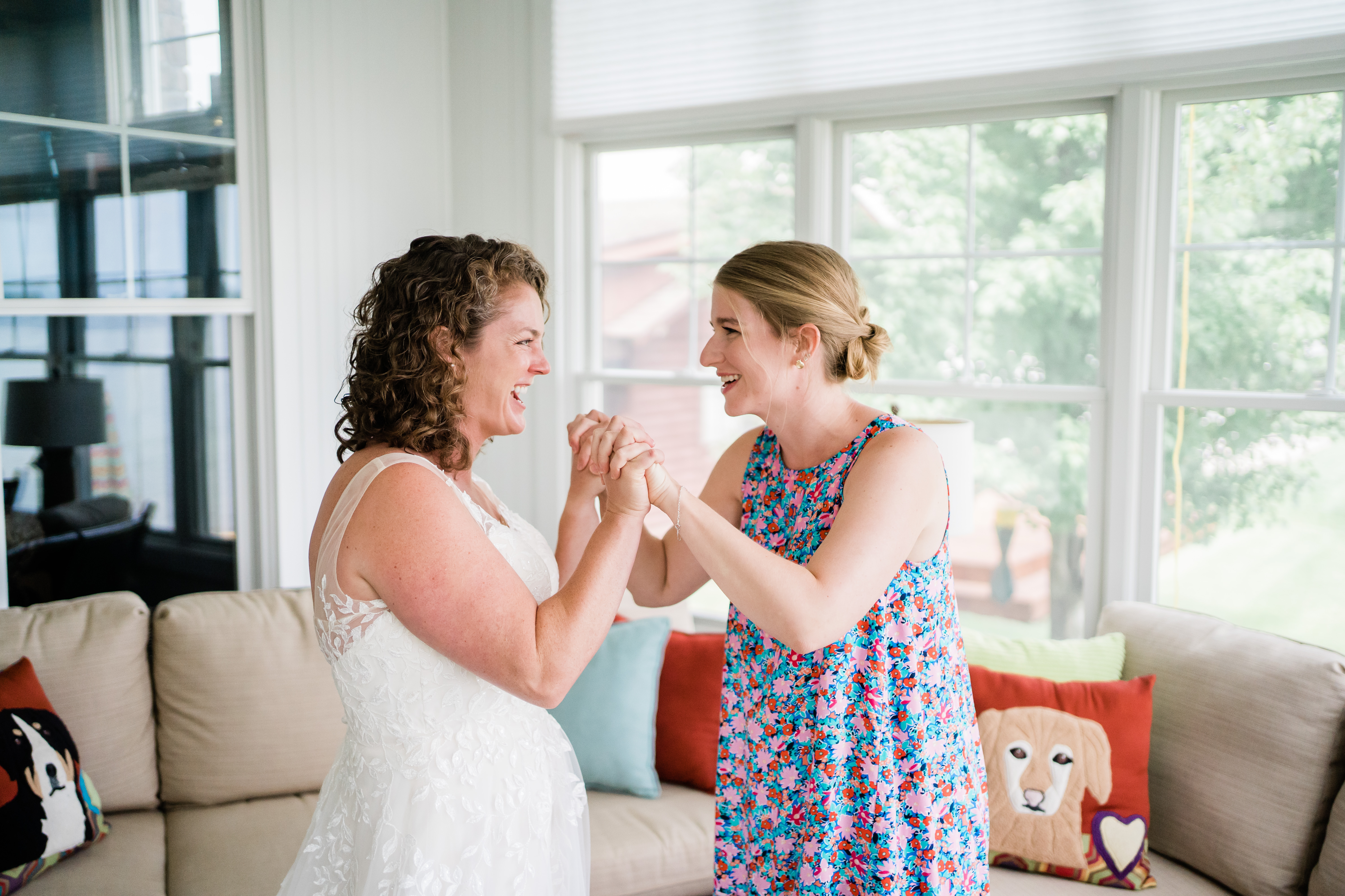 bride and friend holding hands and laughing