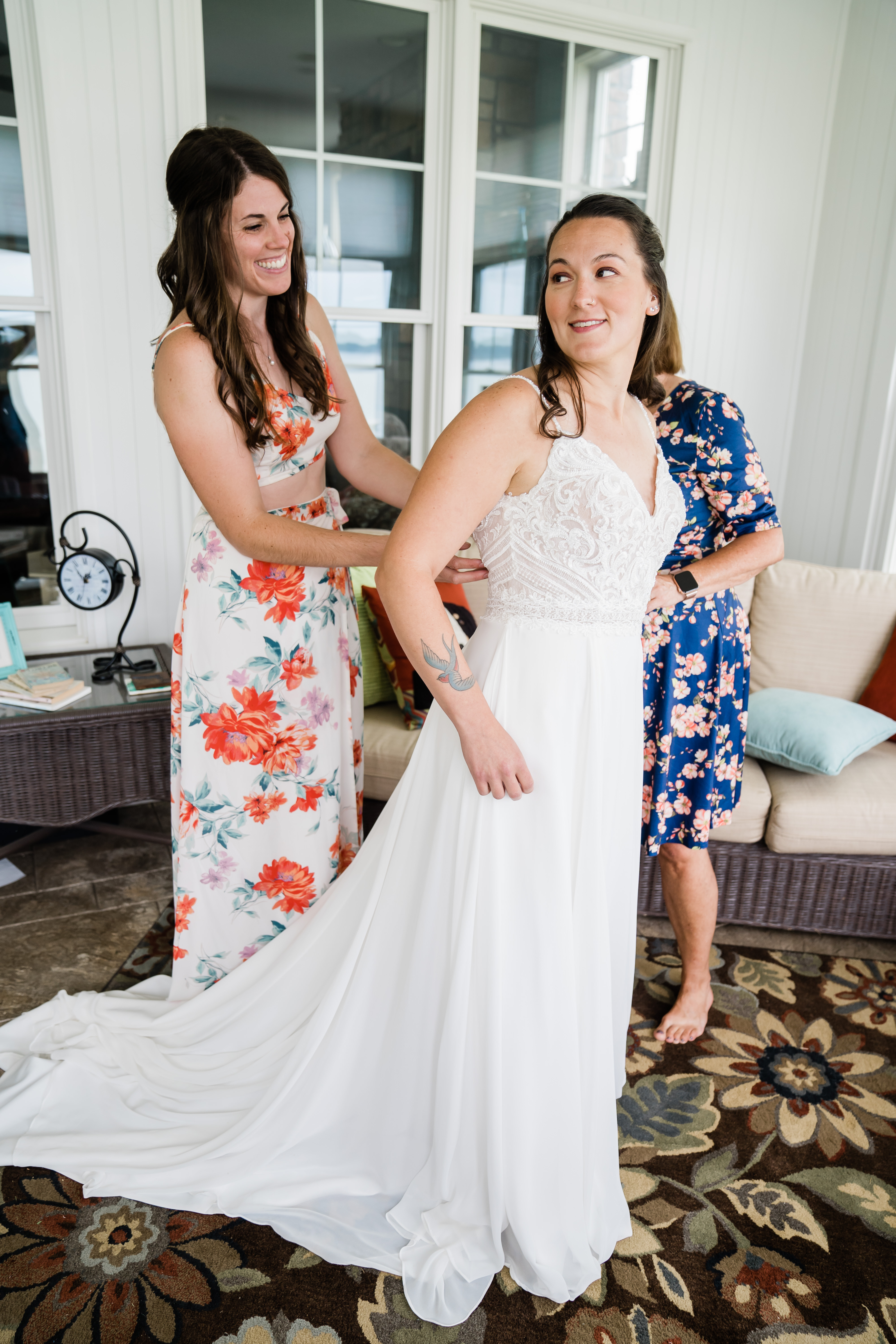 bride smiling while mother and sister help her get ready
