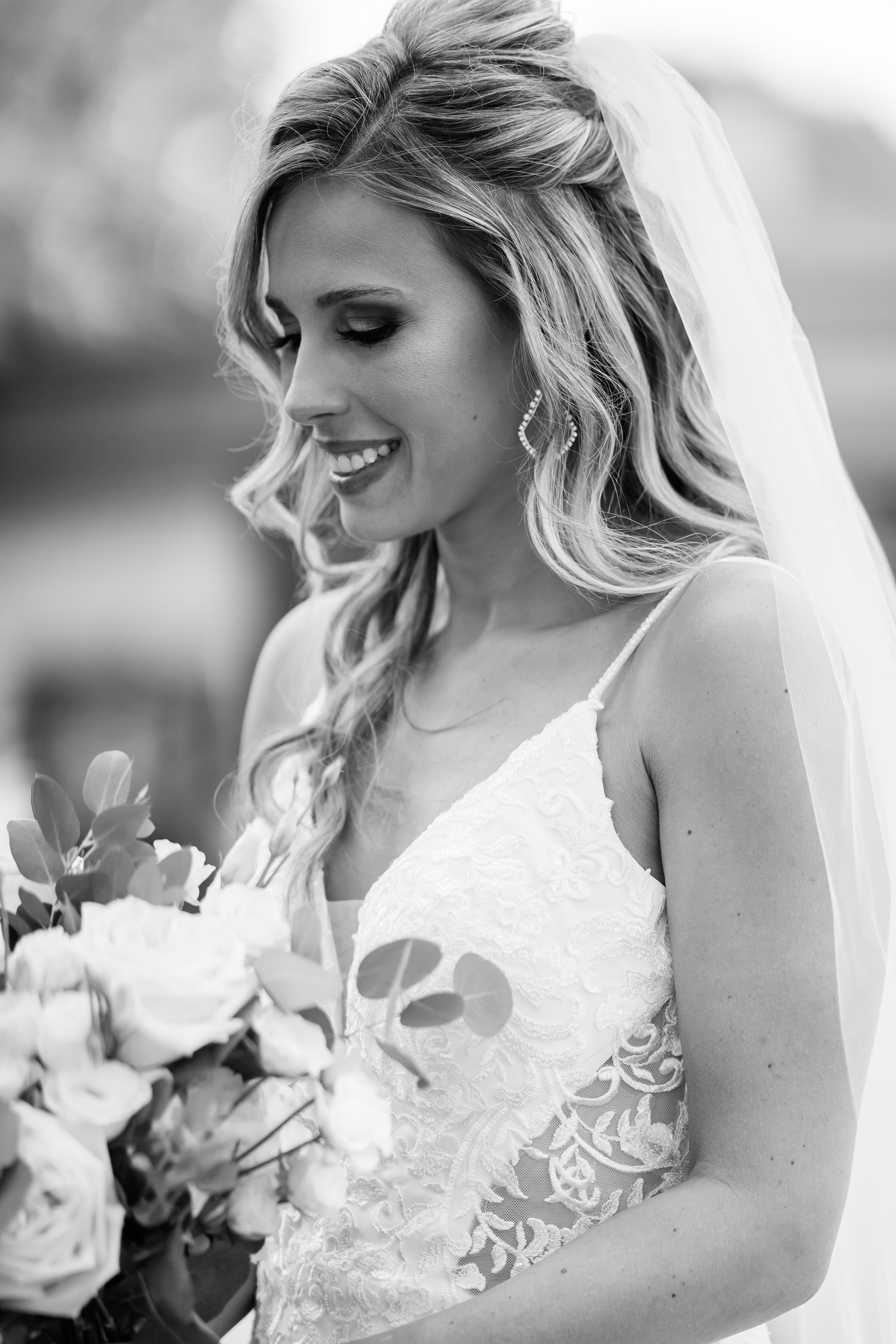 black and white portrait of bride looking down at bouquet