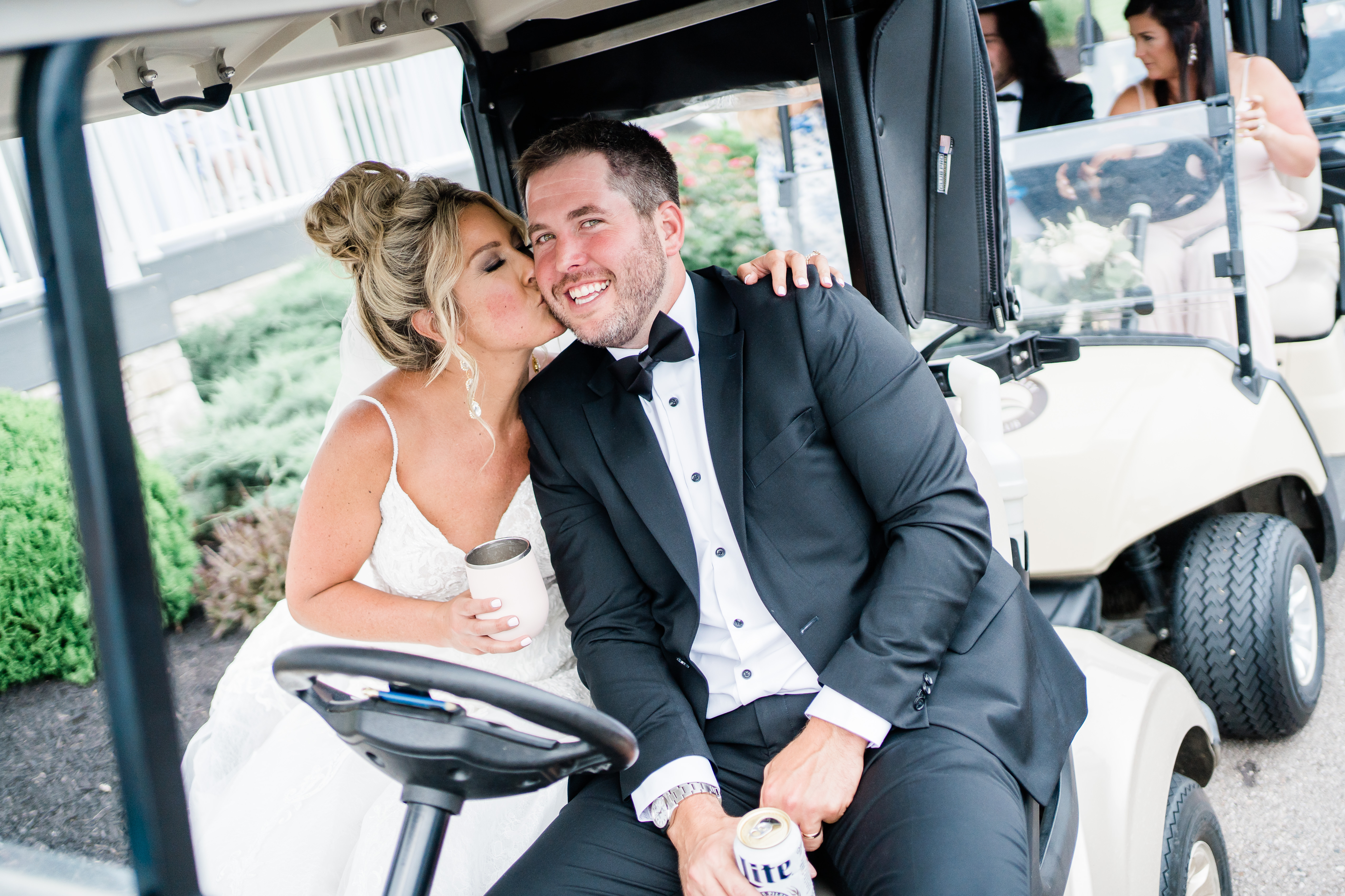 bride kissing groom on cheek while riding in golf cart
