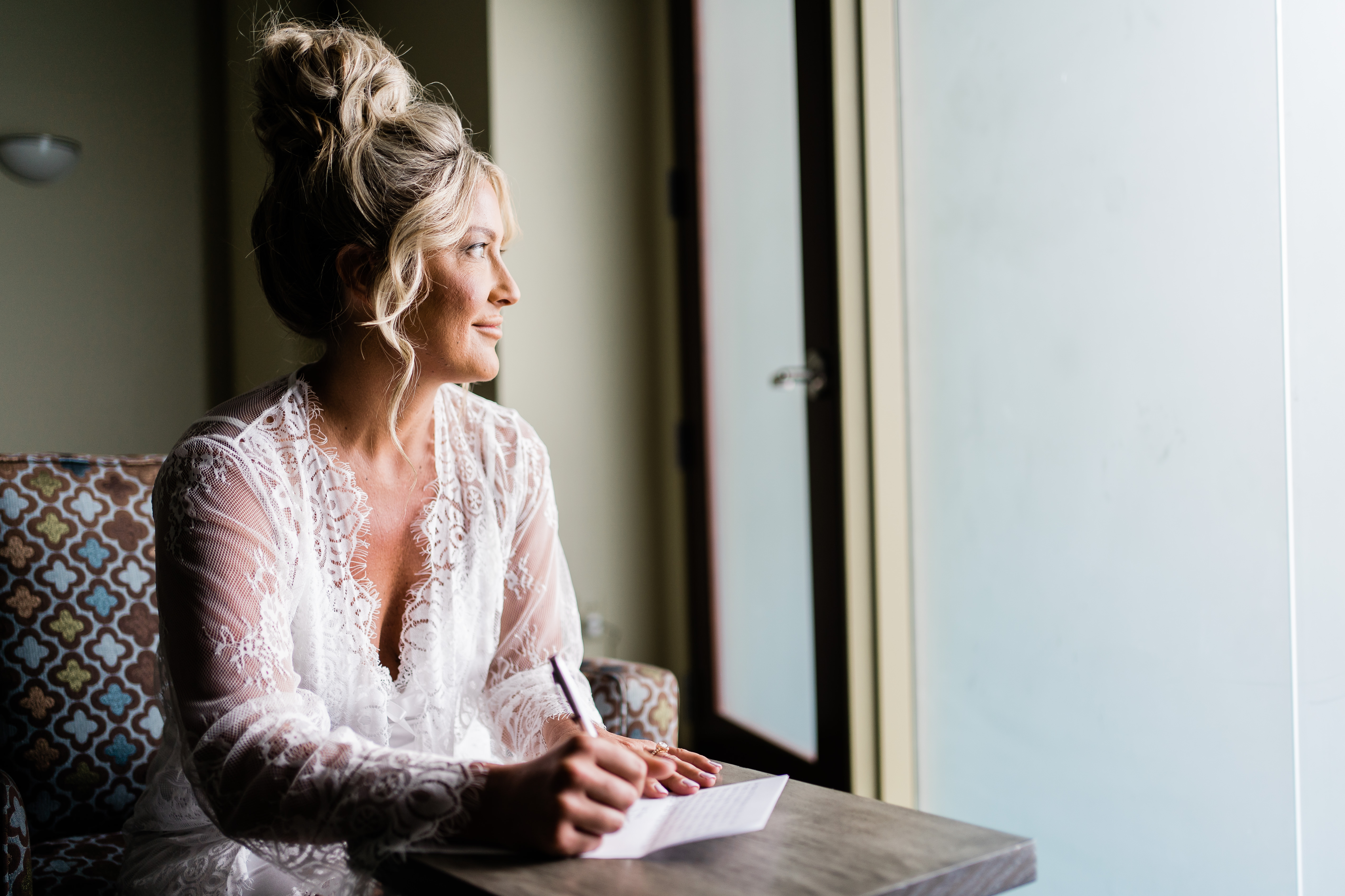 Fort Wayne wedding photographer captures bride writing letter while looking out the window