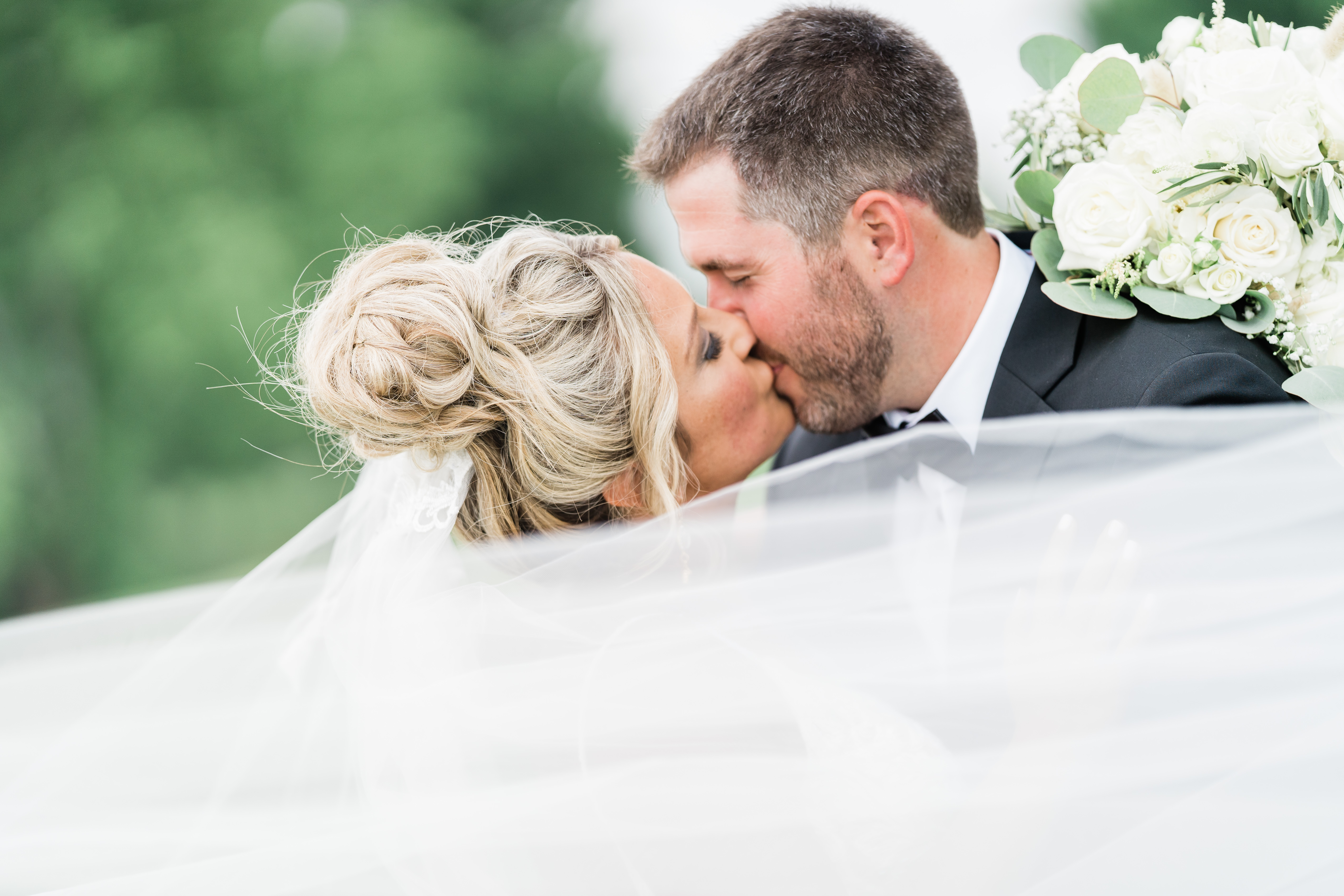 bride and groom kissing through veil