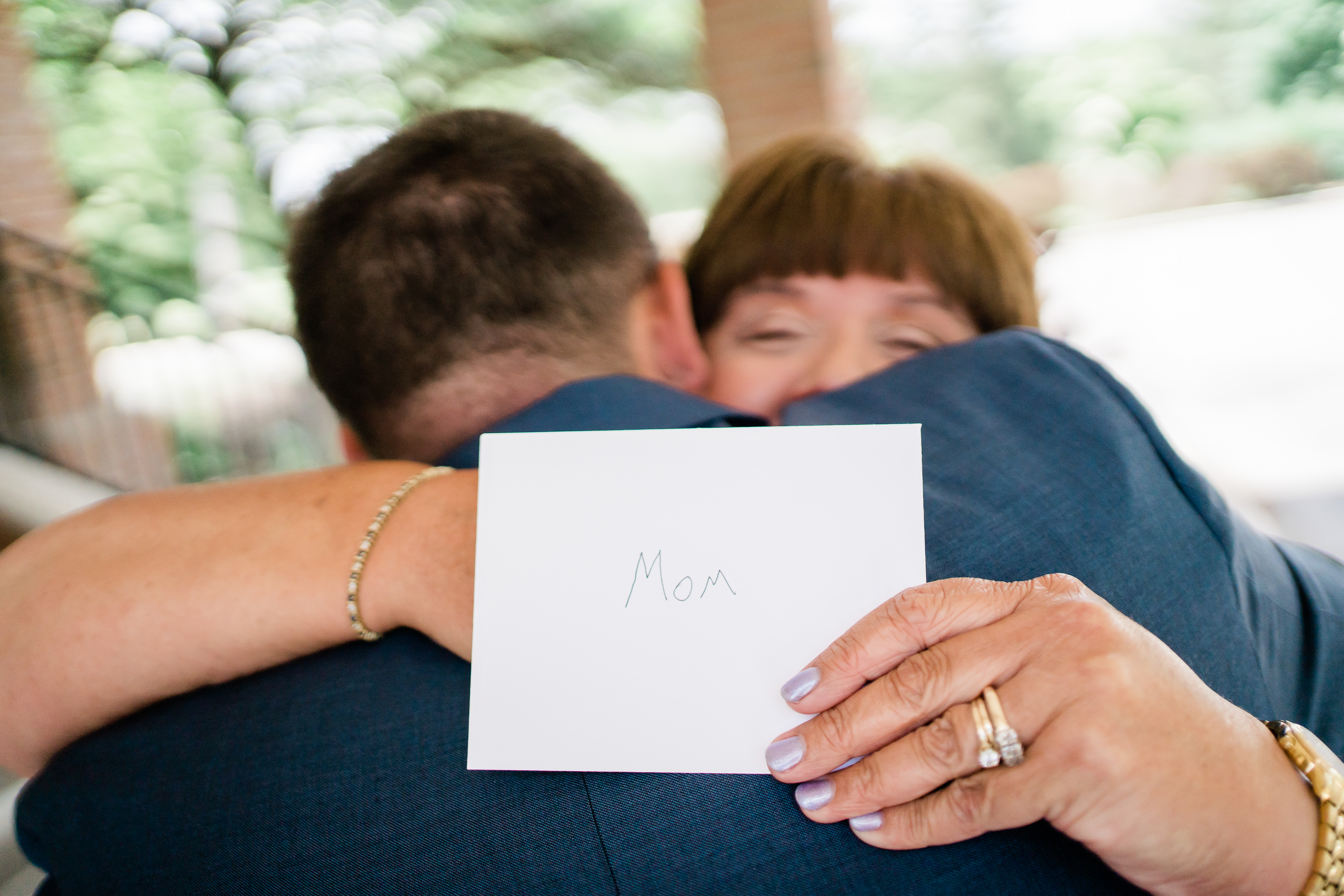 Fort Wayne wedding photographers capture groom's mother hugging groom and holding letter he wrote for her