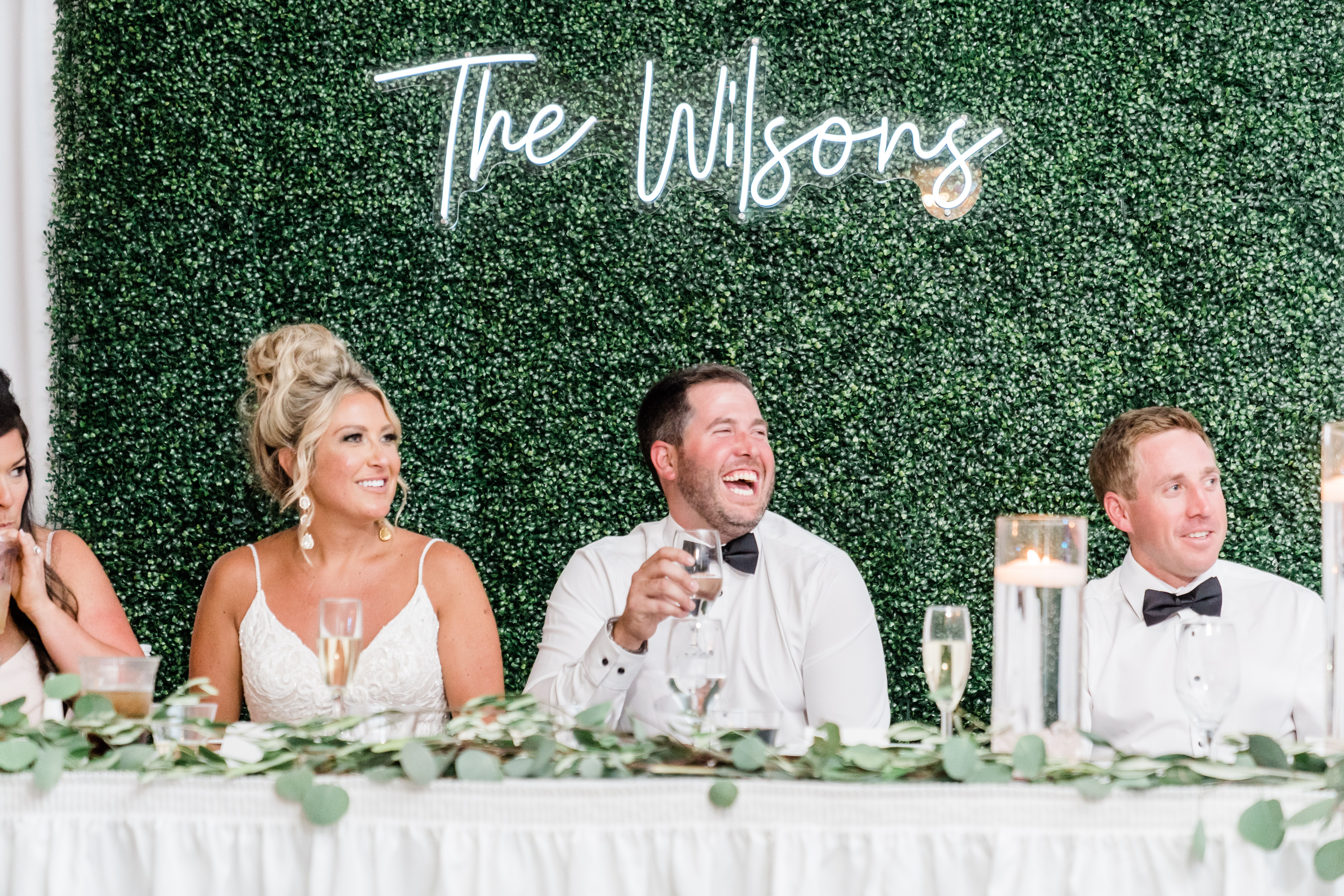 bride and groom laughing while best man gives speech