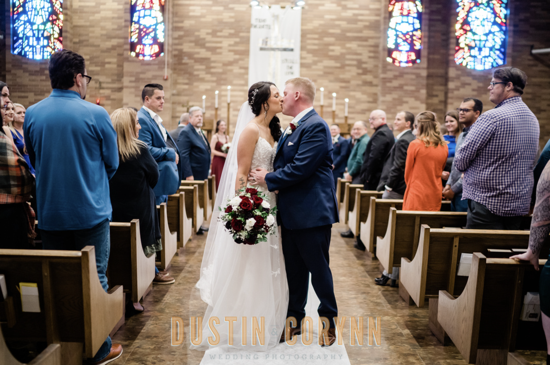 bride and groom kissing as newly married couple while walking down the aisle